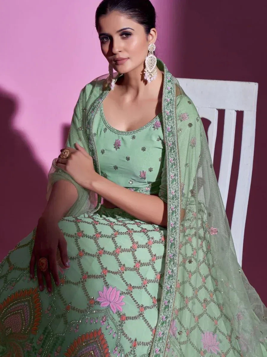 Mint green designer lehenga choli with floral embroidery and net dupatta, perfect for Indian ethnic occasions.