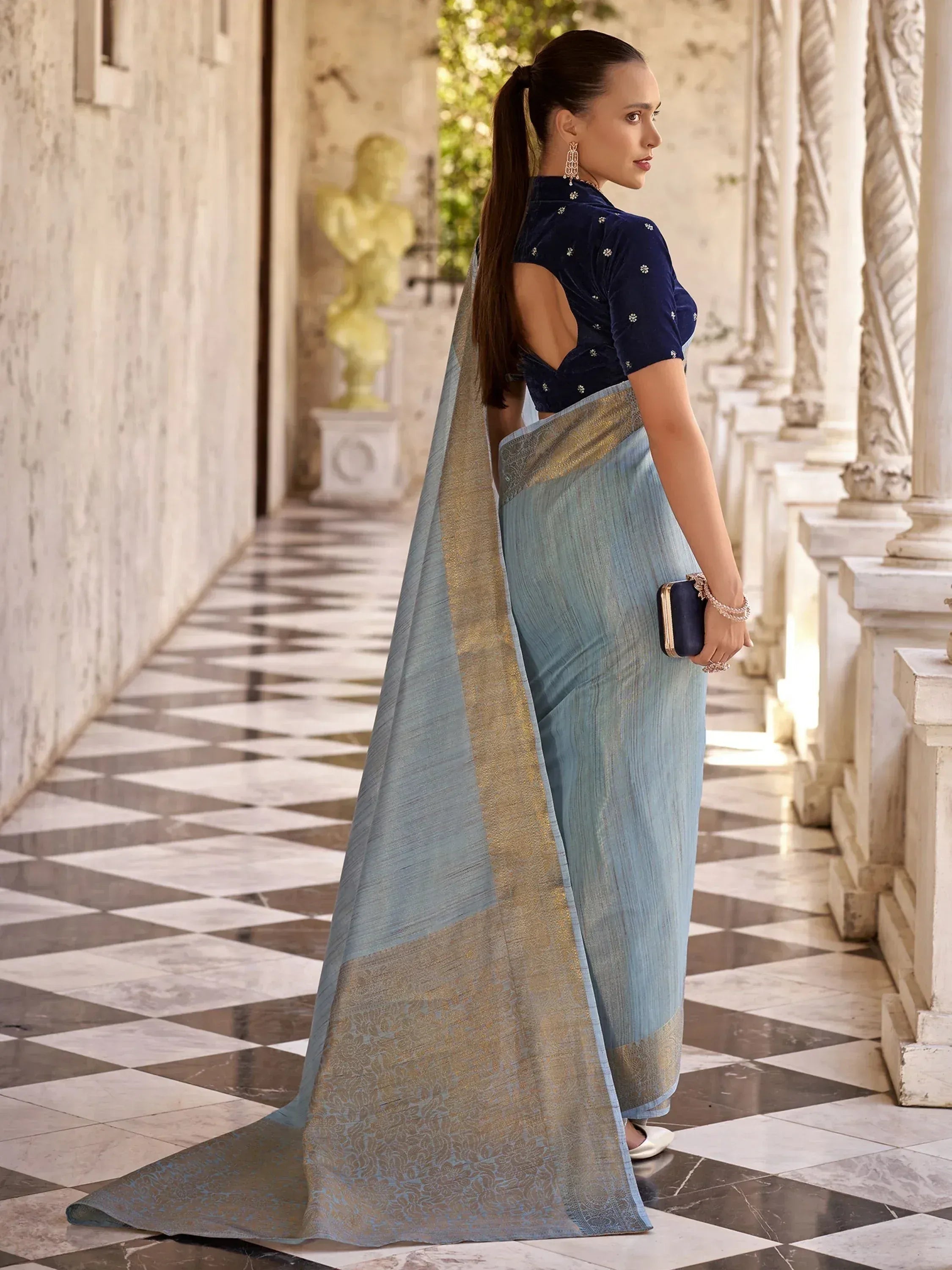 Woman in light blue saree with gold border and navy velvet blouse, elegant ethnic wear for special occasions