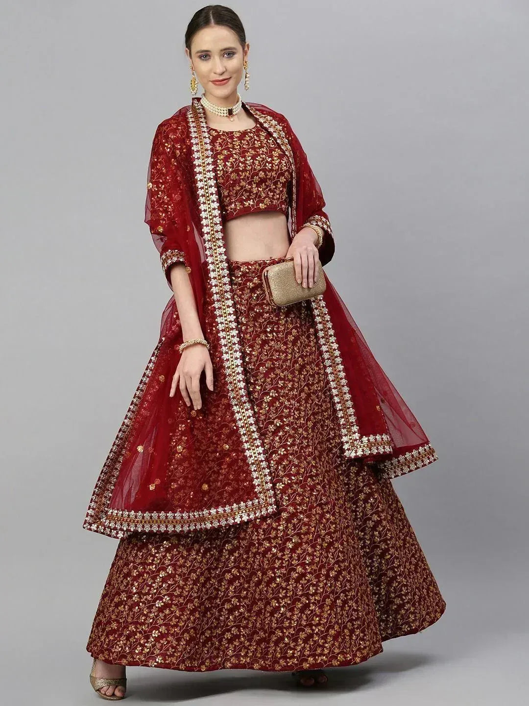 Red embroidered lehenga choli with gold floral work, dupatta, and pearl jewelry for Indian weddings