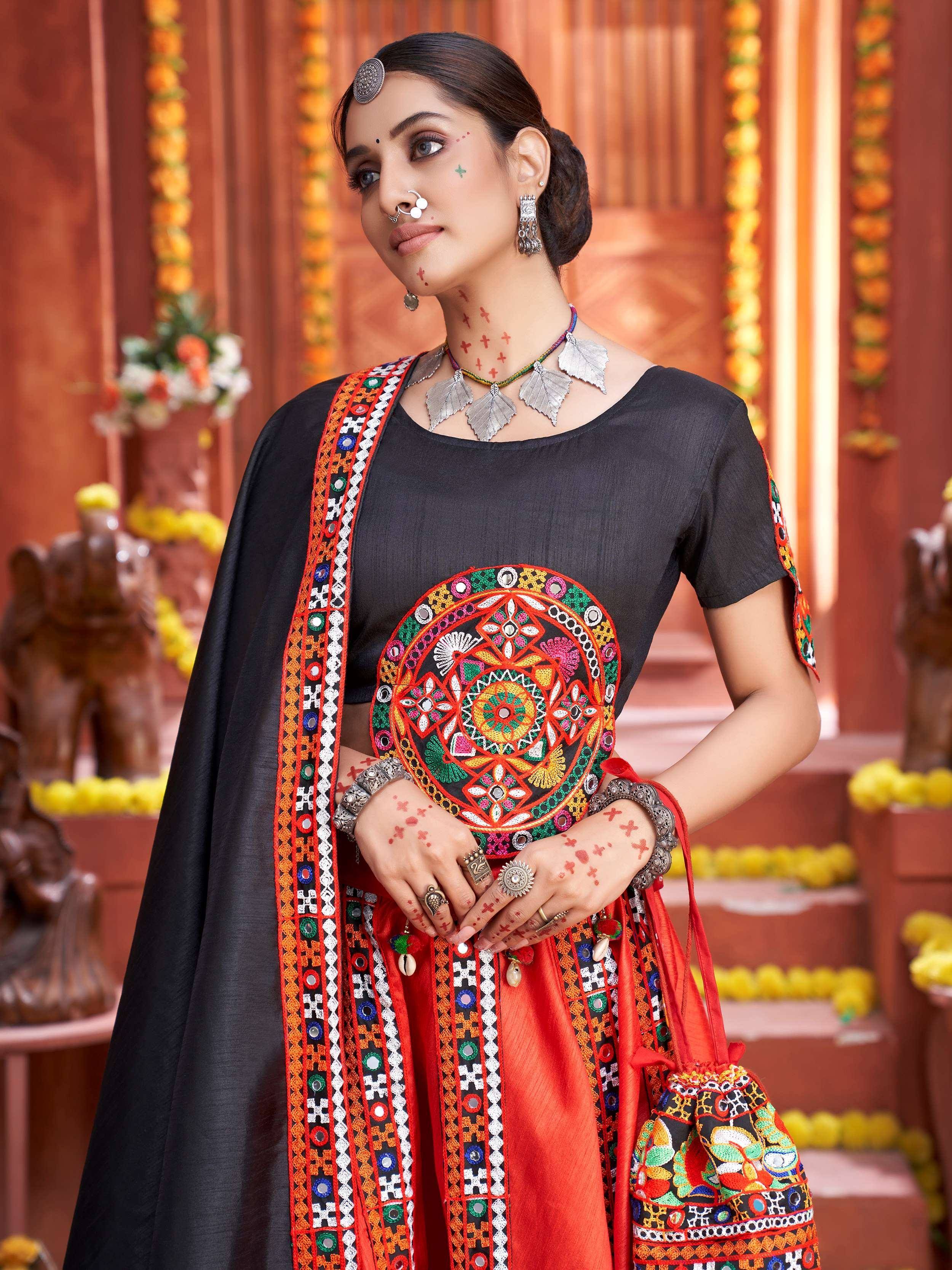 Black and red embroidered ethnic wear with mirror work, traditional jewelry, and festive floral backdrop