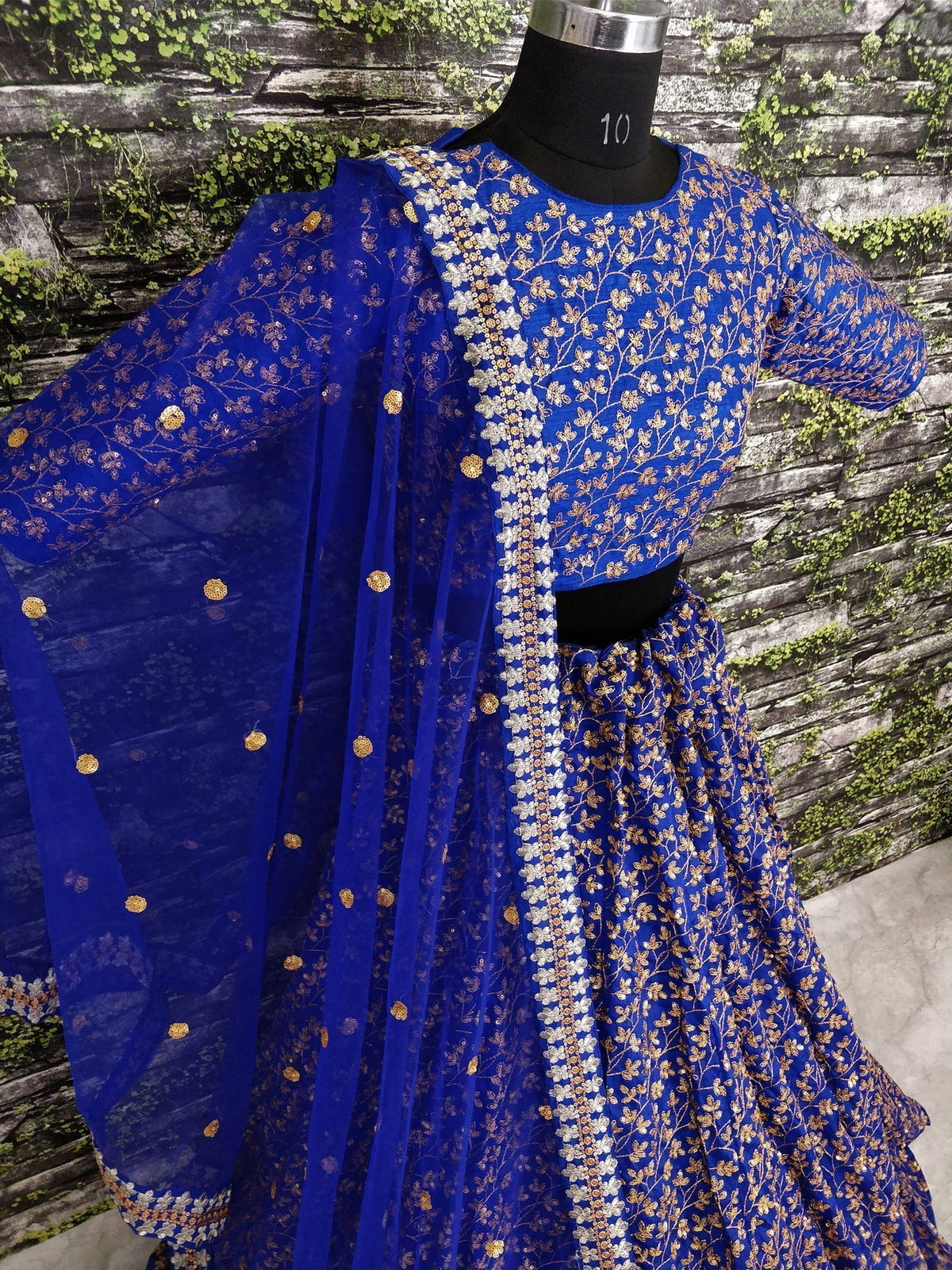 Royal blue embroidered lehenga choli with gold floral work and matching dupatta, displayed on mannequin