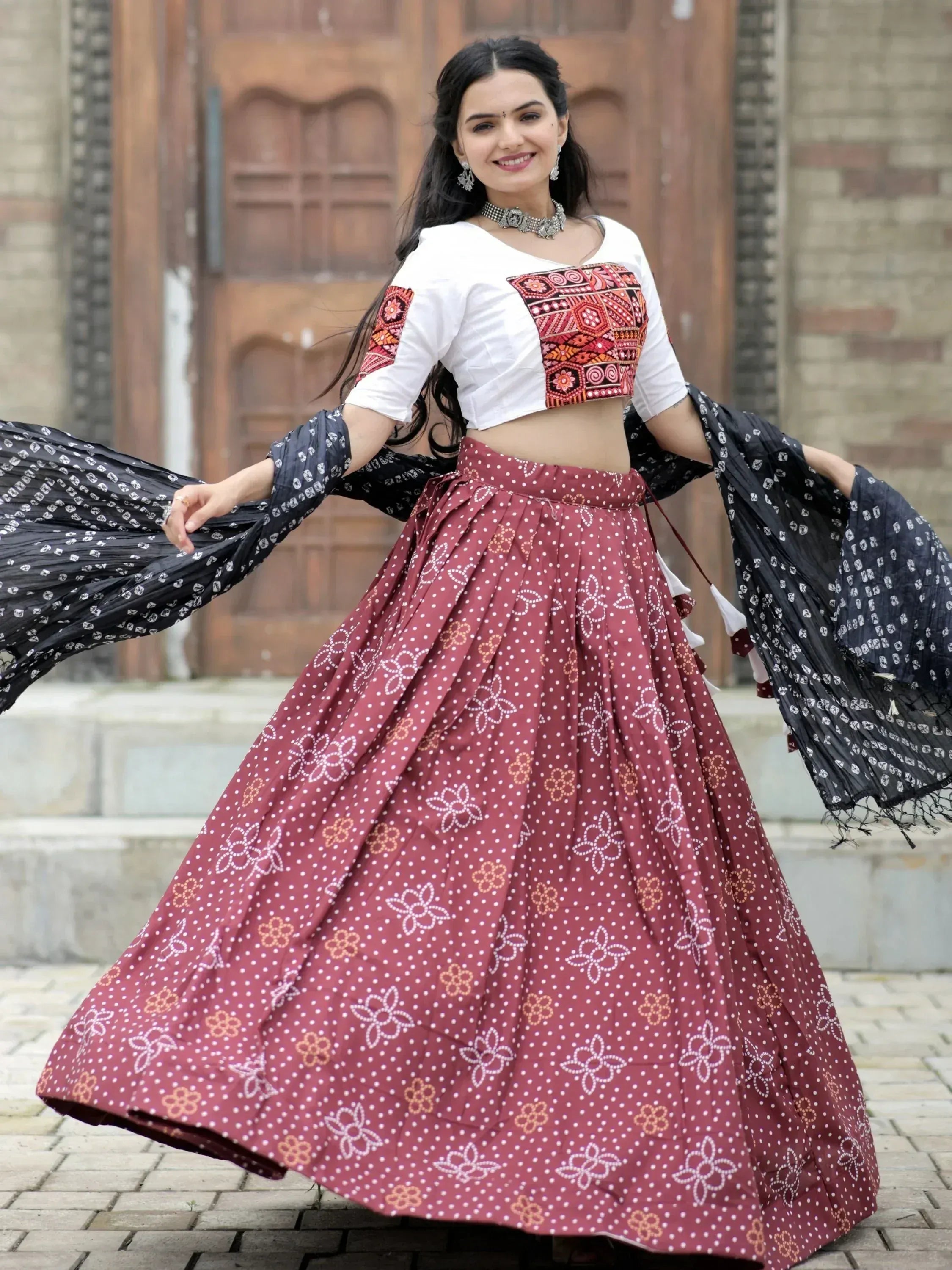 Woman in ethnic Indian lehenga choli with printed skirt and embroidered blouse, twirling outdoors