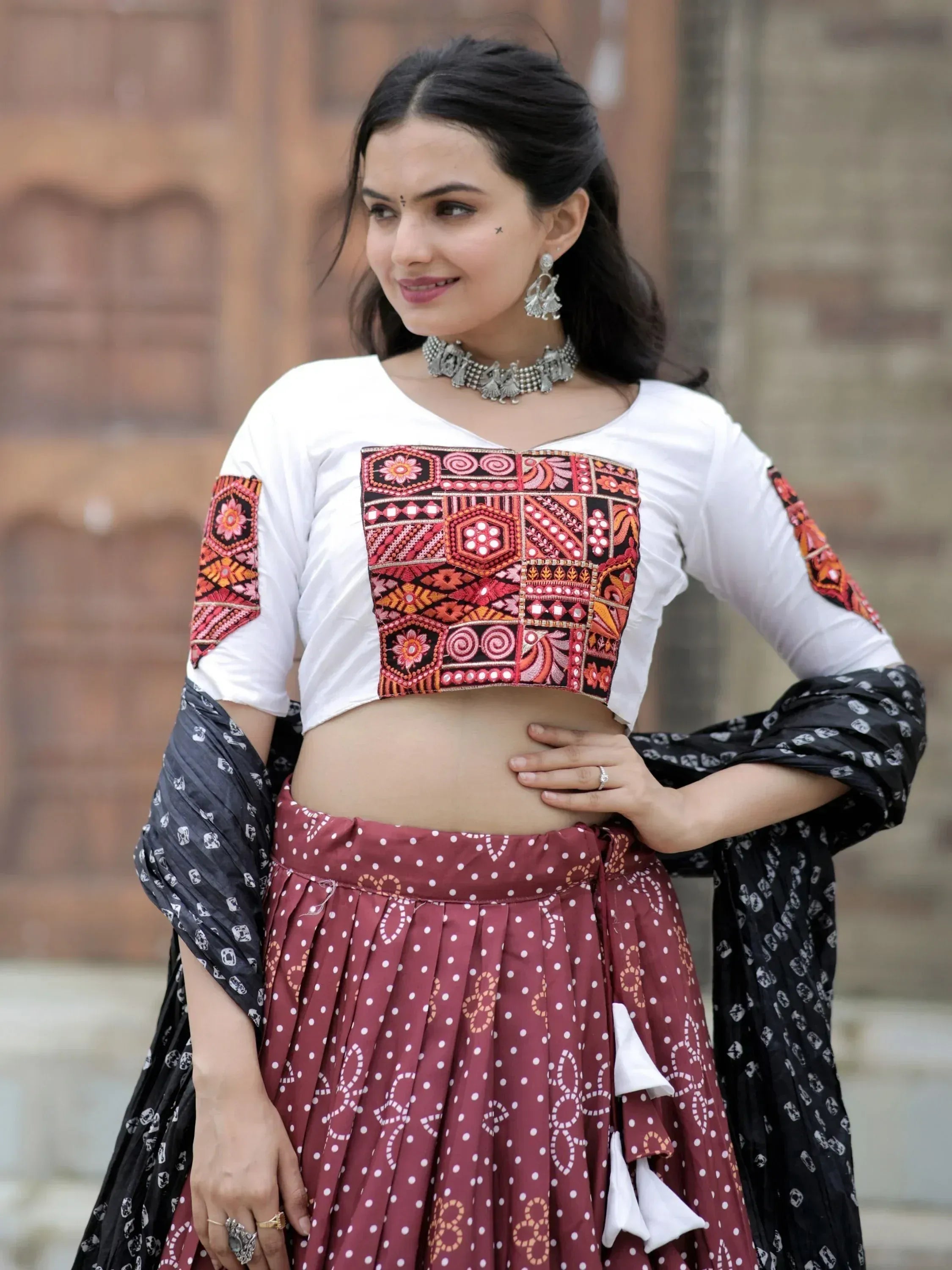 Woman in embroidered white crop top with red patterned skirt, ethnic Indian wear