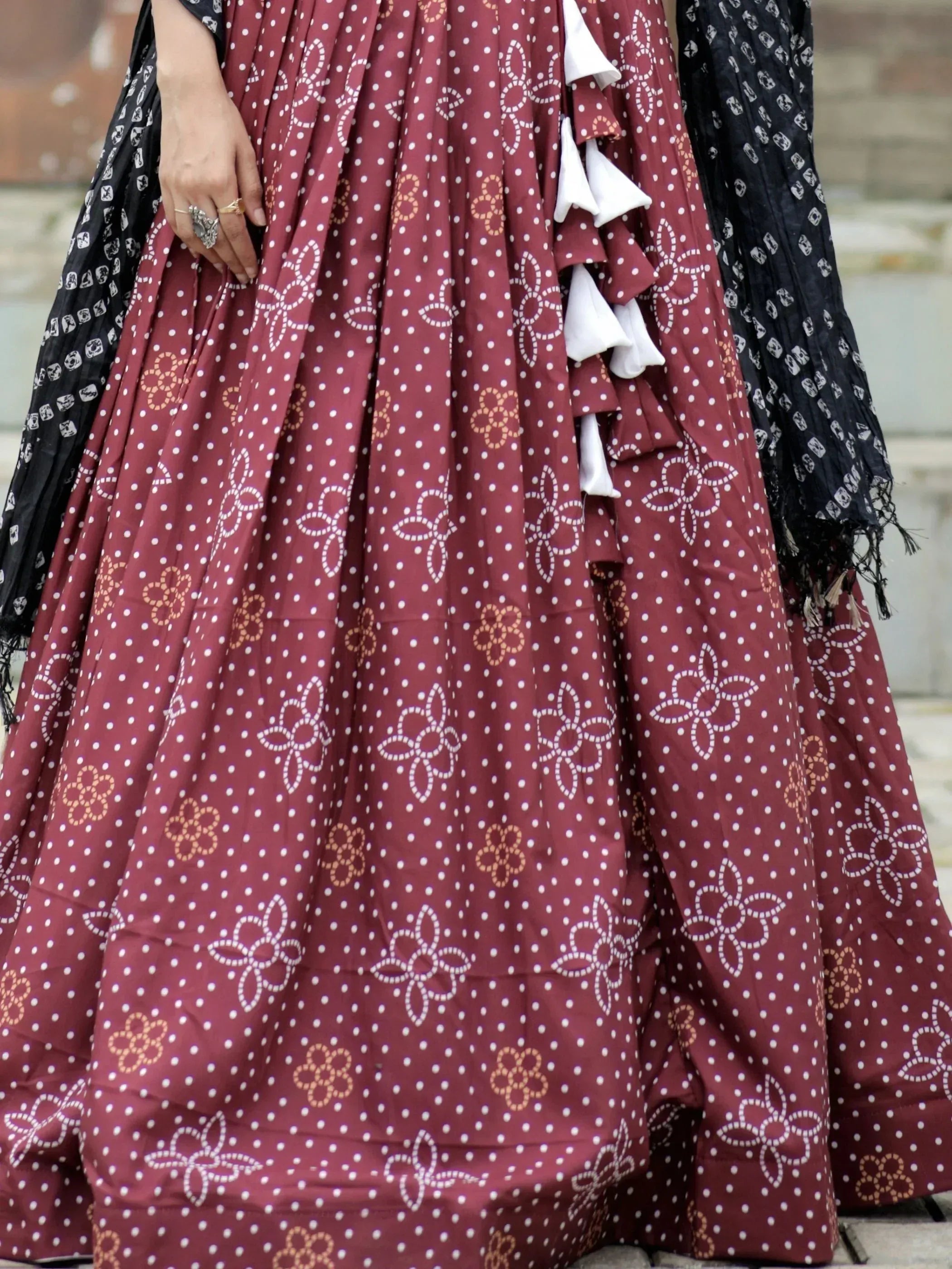 Maroon ethnic gown with white polka dots and floral print, paired with black dupatta, perfect for Indian occasions.