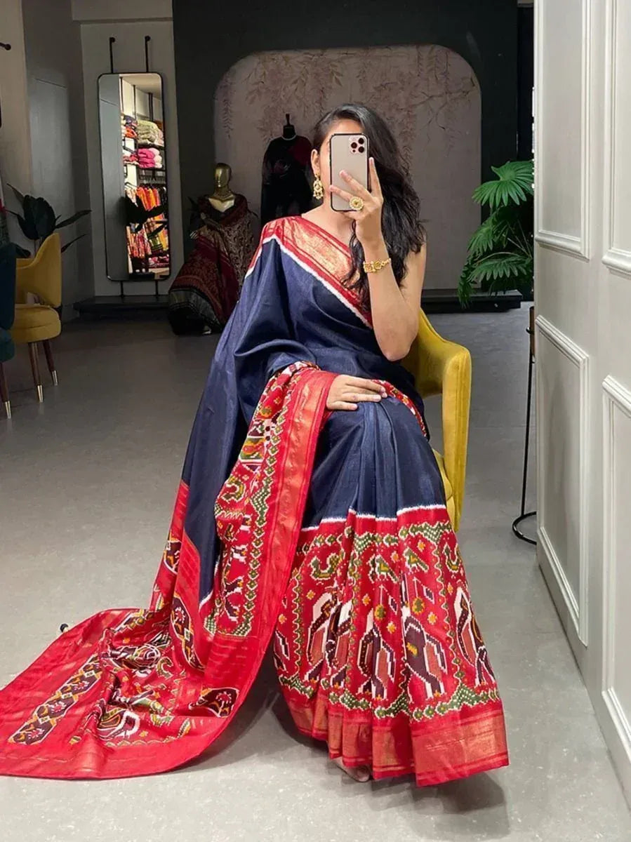 Woman in navy blue and red printed saree with ethnic border, seated in boutique setting
