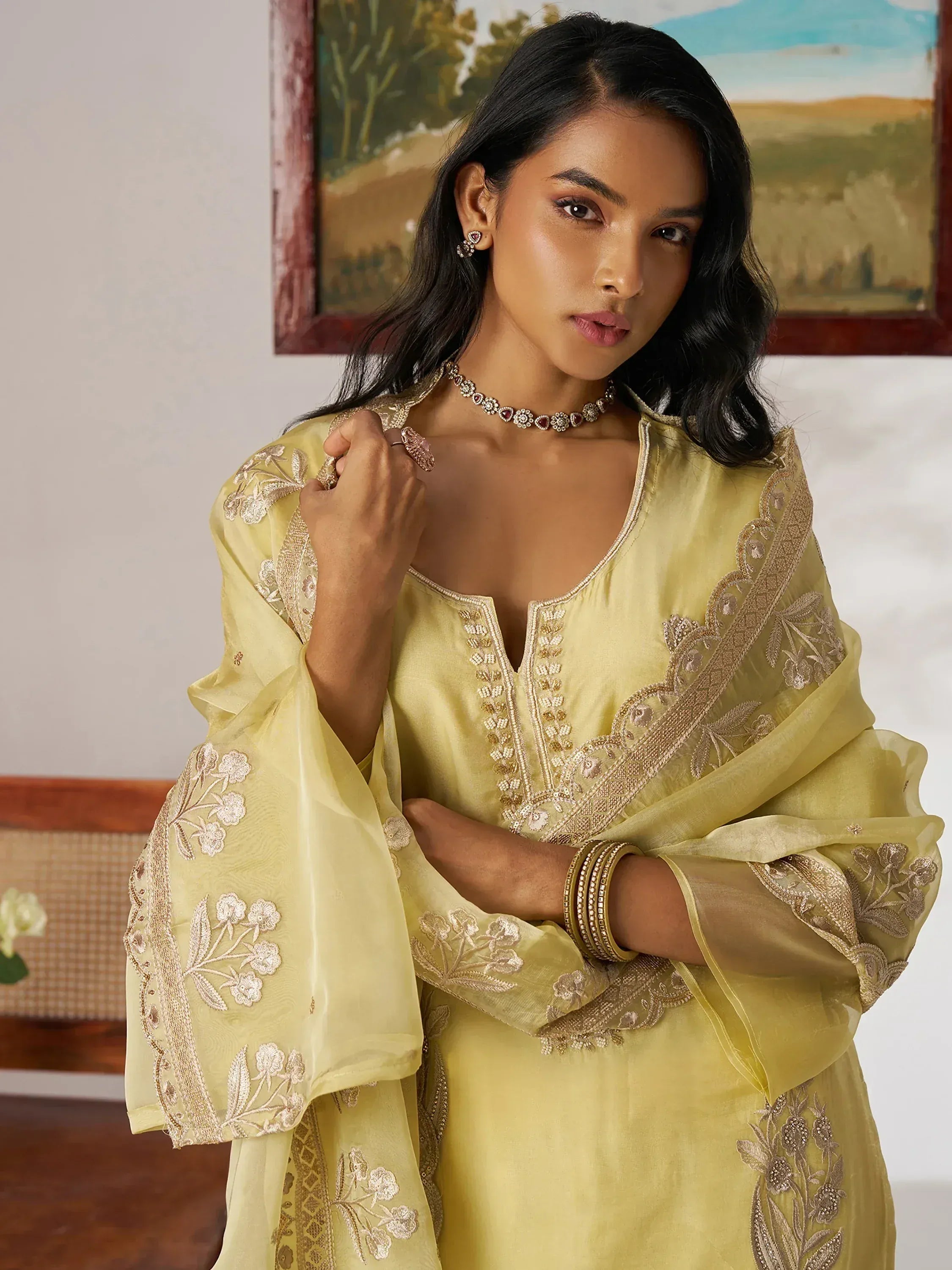 Yellow embroidered ethnic gown with floral detailing and gold trim, styled with traditional jewelry