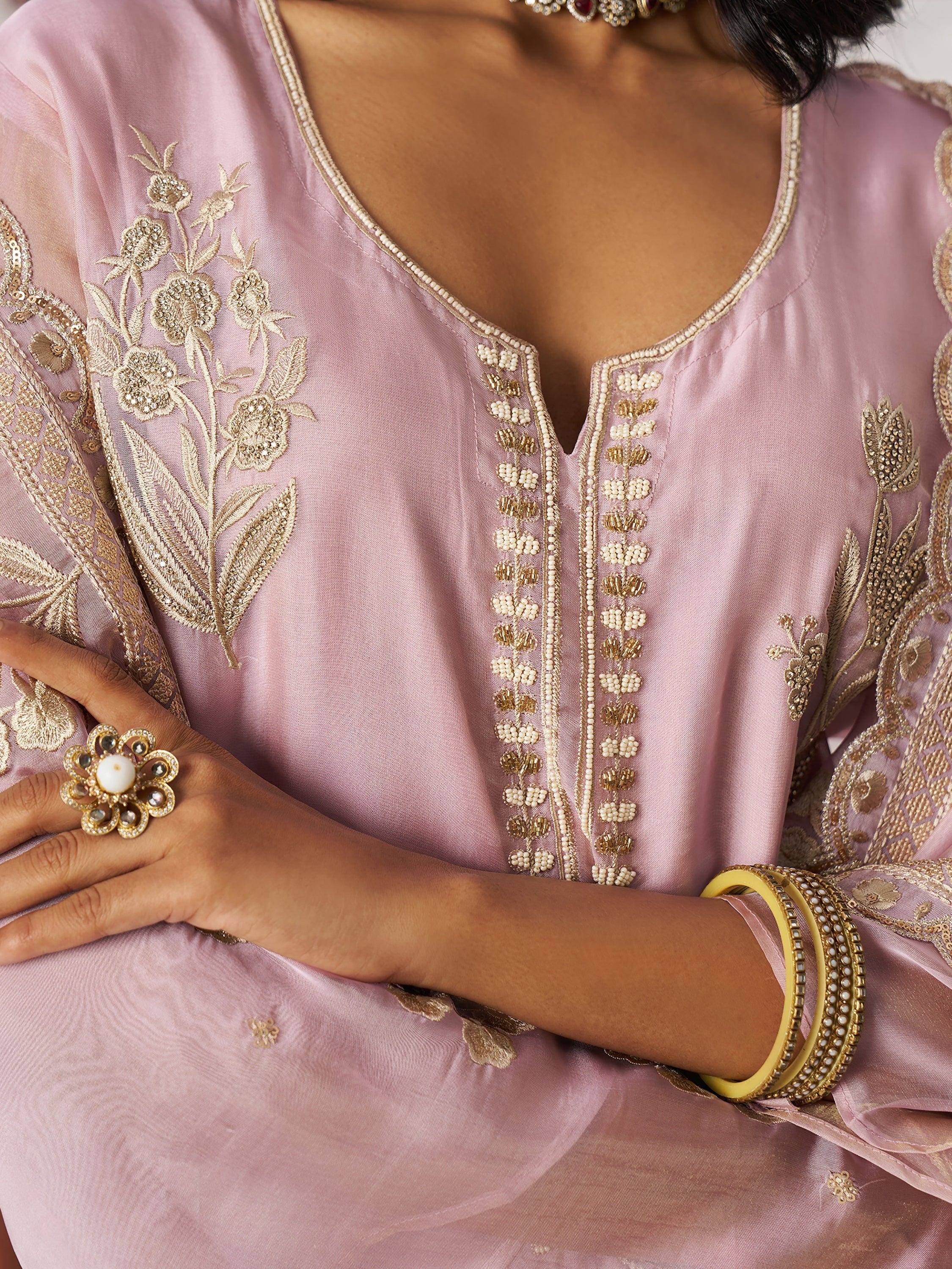 Pink ethnic kurti with gold floral embroidery and beadwork, paired with statement jewelry for festive occasions.