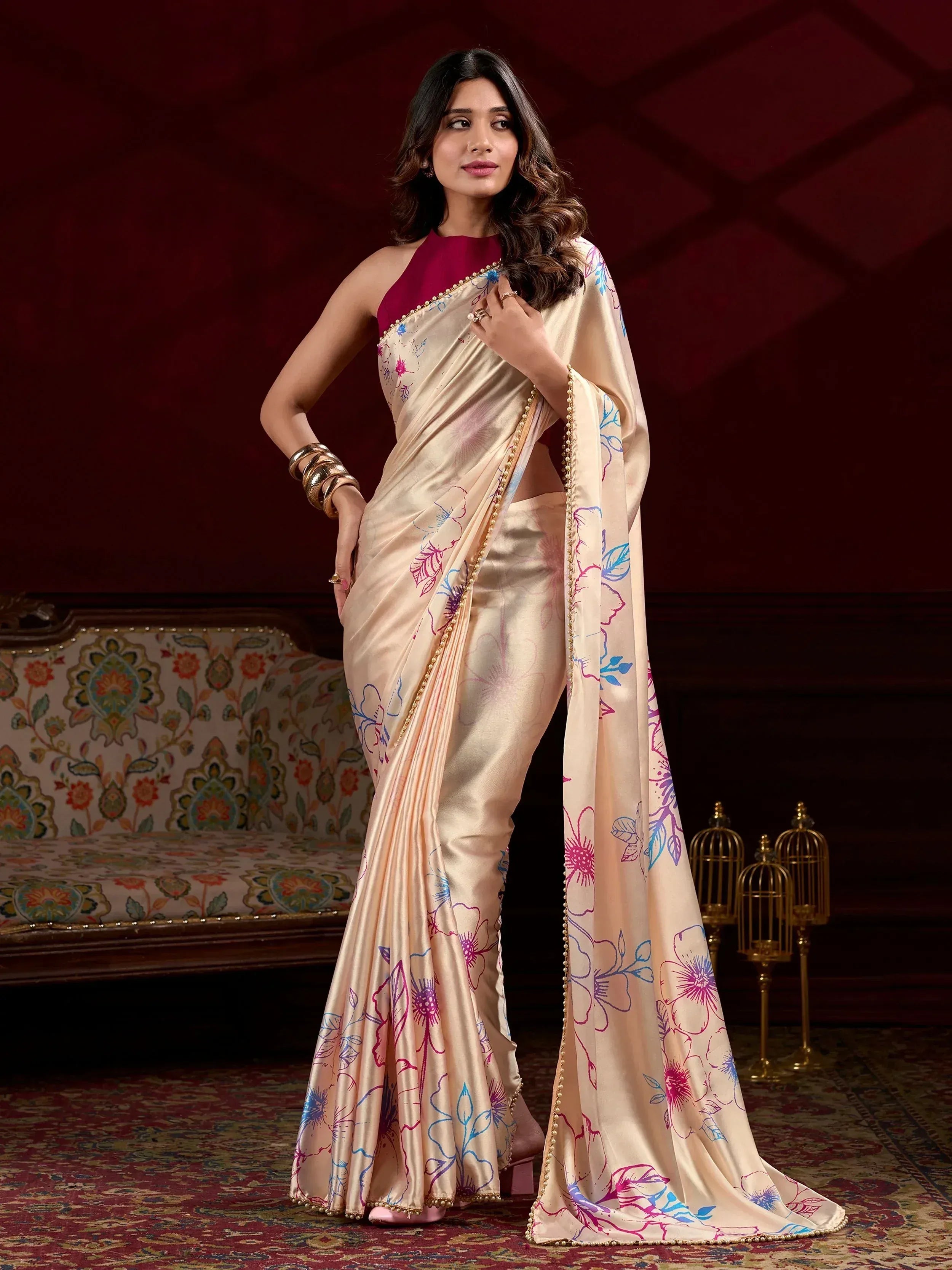 Elegant cream saree with colorful floral print and gold border, paired with maroon blouse, perfect for Indian ethnic occasions.
