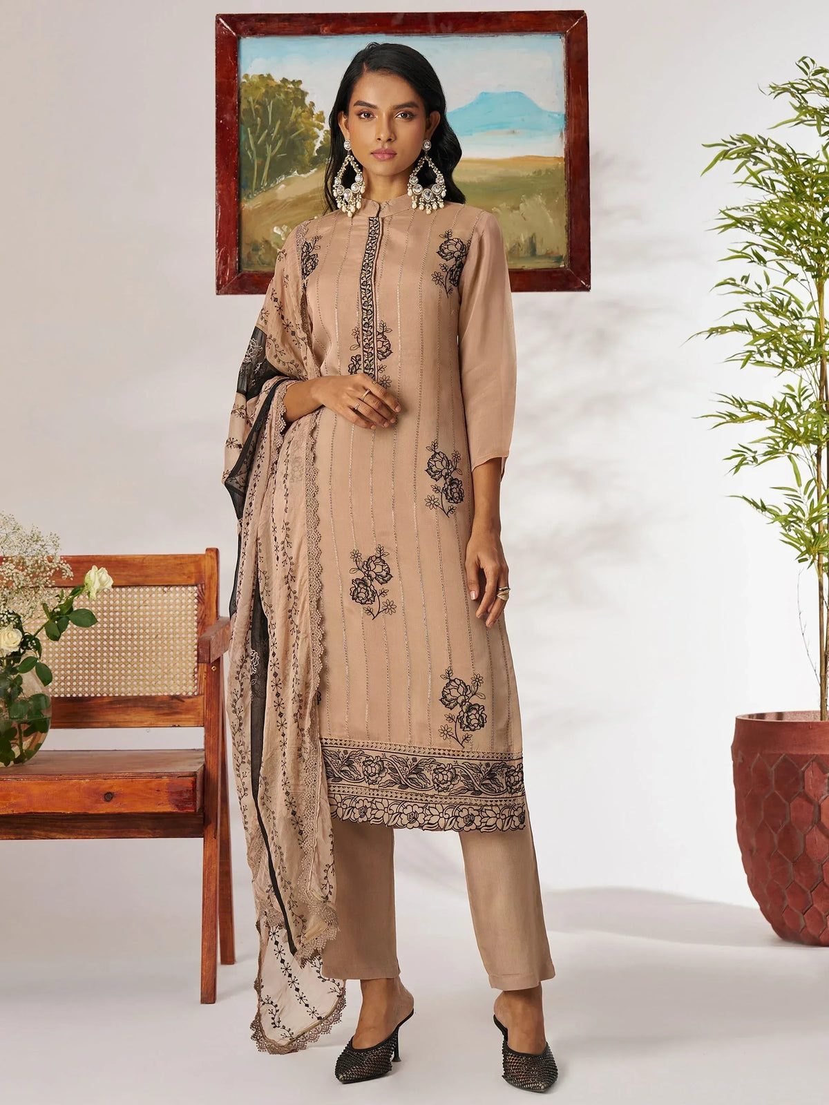 Beige embroidered salwar kameez with black floral detailing and matching dupatta, styled with statement earrings.