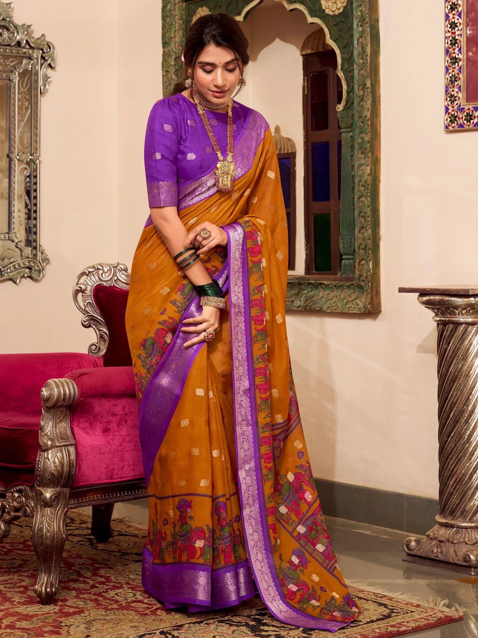 Woman in mustard and purple ethnic saree with elephant print, traditional Indian wear for festive occasions