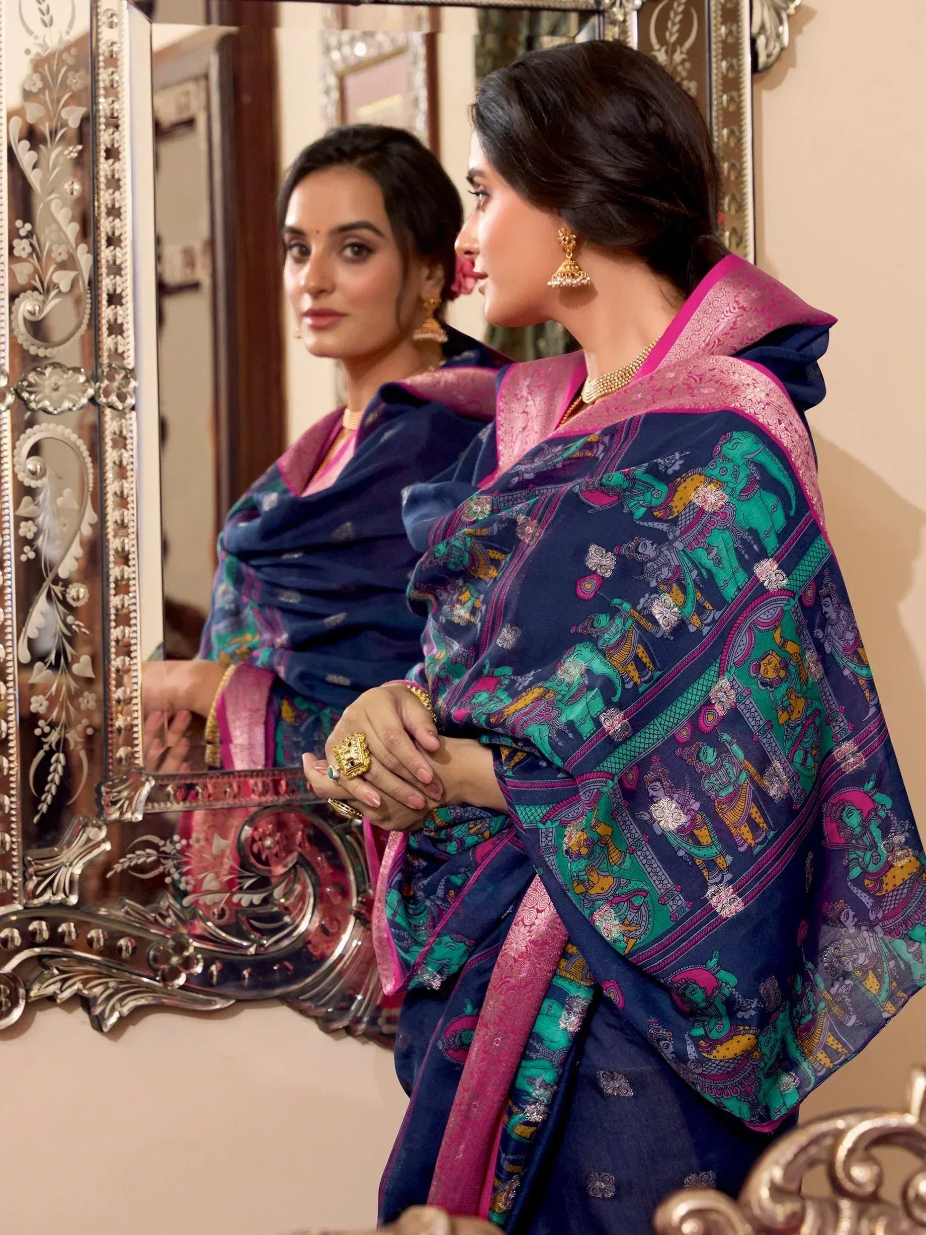 Woman in navy blue saree with colorful elephant print and pink border, traditional Indian ethnic wear