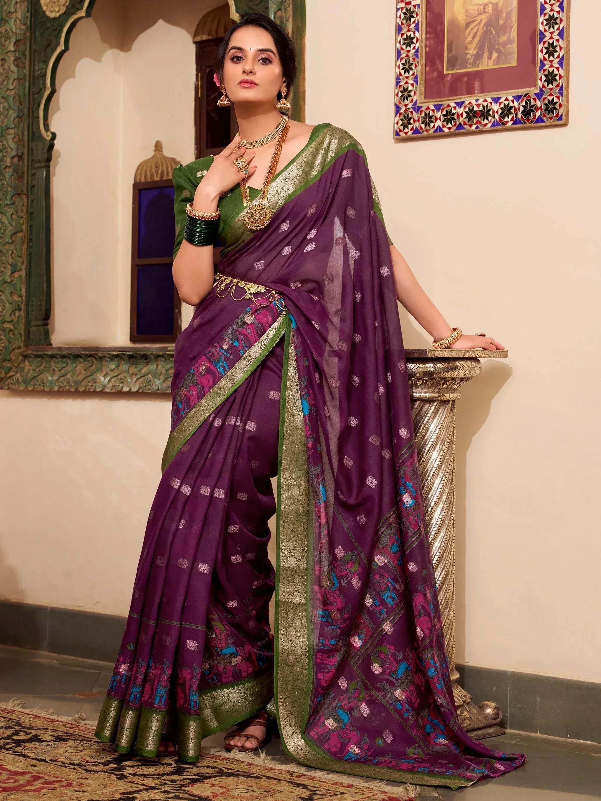 Woman in purple and green designer saree with elephant print, gold jewelry, traditional Indian ethnic wear