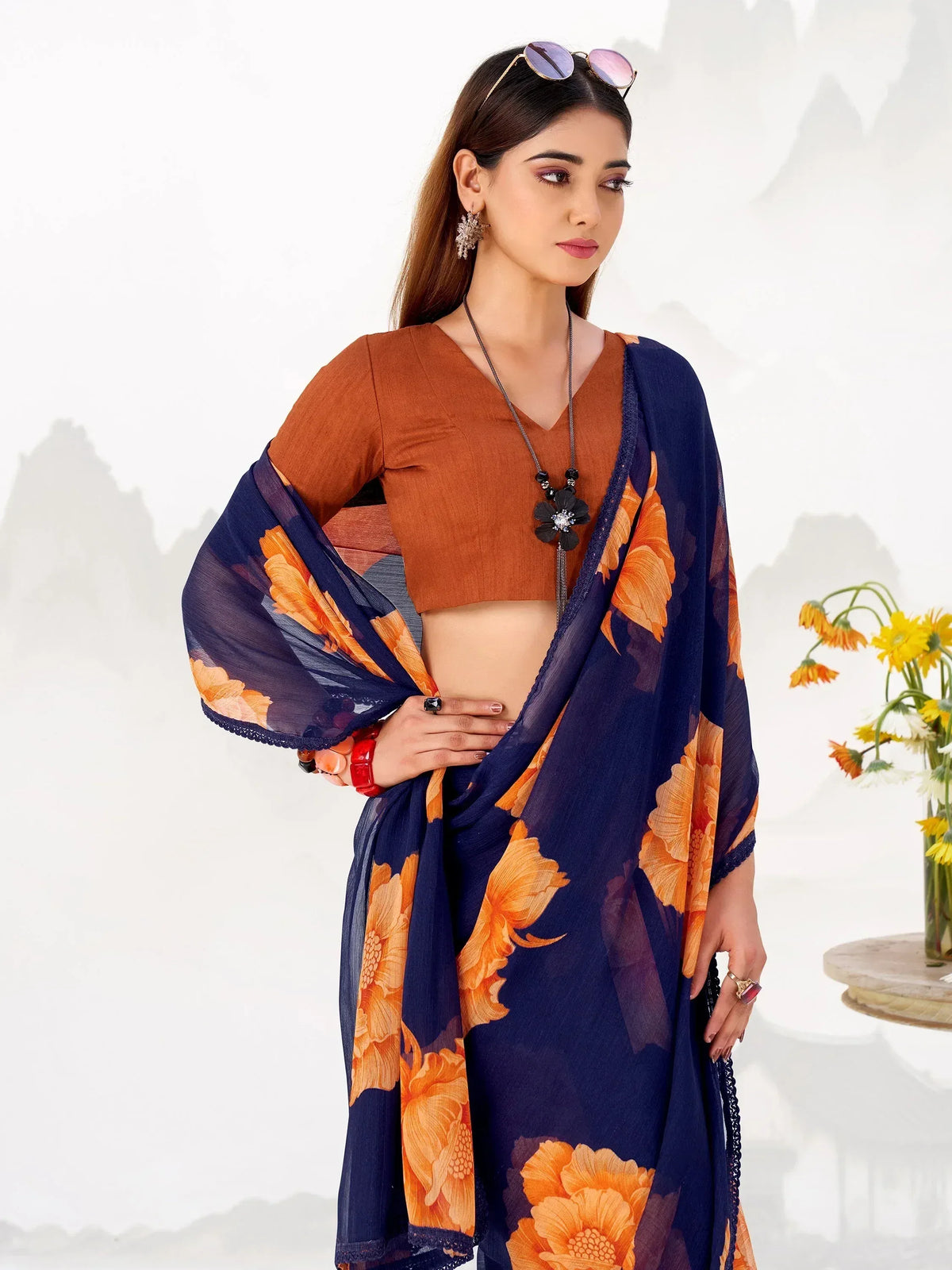 Stylish navy blue saree with orange floral print paired with a brown blouse, perfect for ethnic occasions.