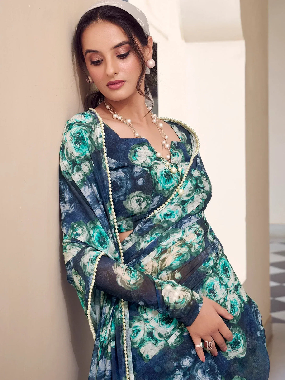 Woman in blue floral ethnic gown with pearl jewelry and headscarf, styled for Indian occasions