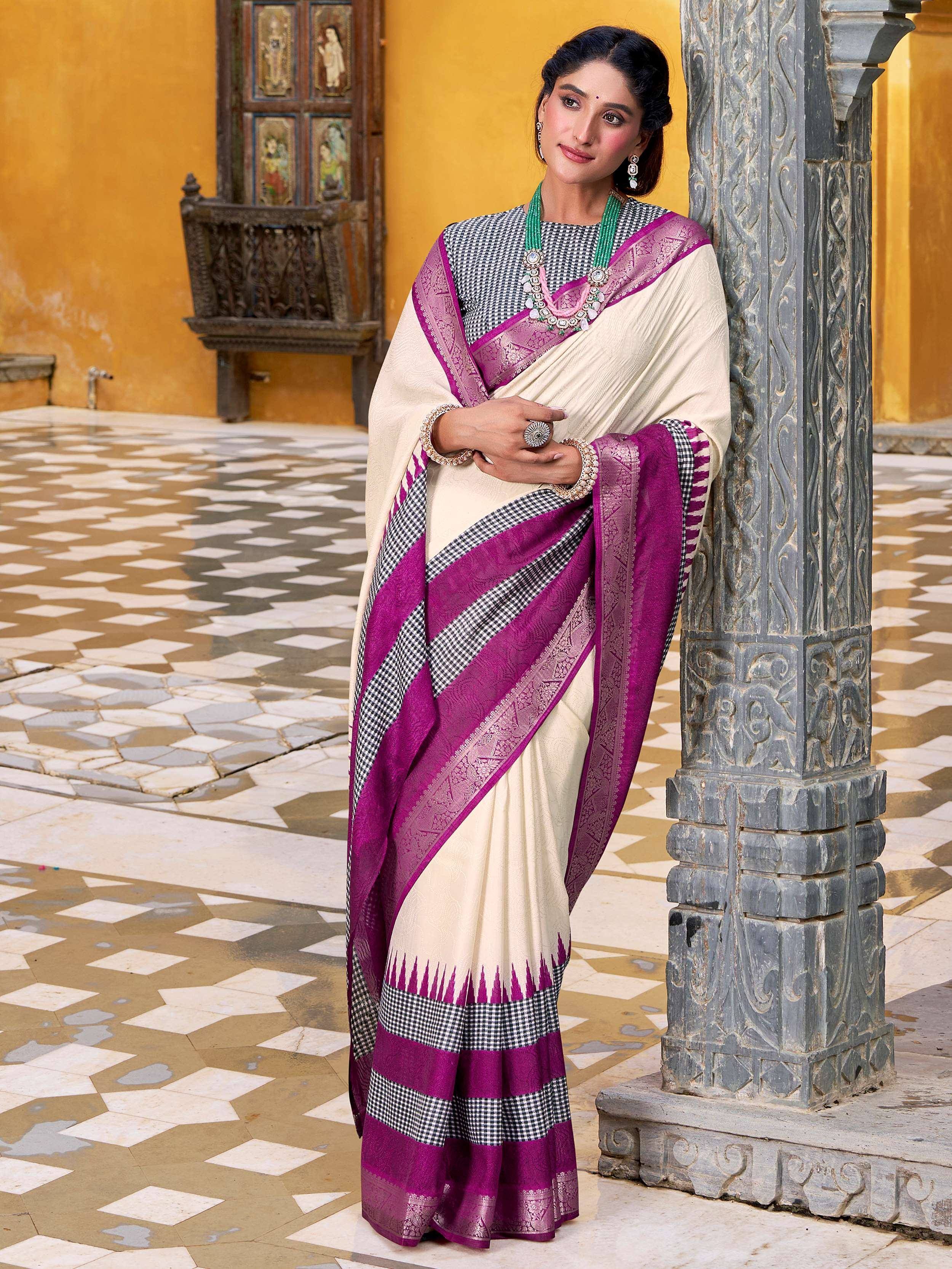 Cream and purple ethnic saree with checkered border, worn with matching blouse and jewelry, ideal for Indian occasions.