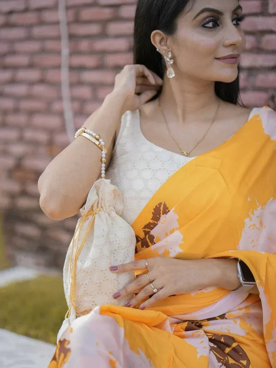 Woman in yellow floral saree with white blouse, pearl jewelry, and drawstring potli bag, styled for ethnic occasions