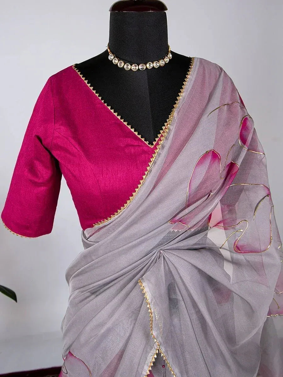 Grey saree with pink floral print and gold trim, paired with magenta blouse, displayed on mannequin
