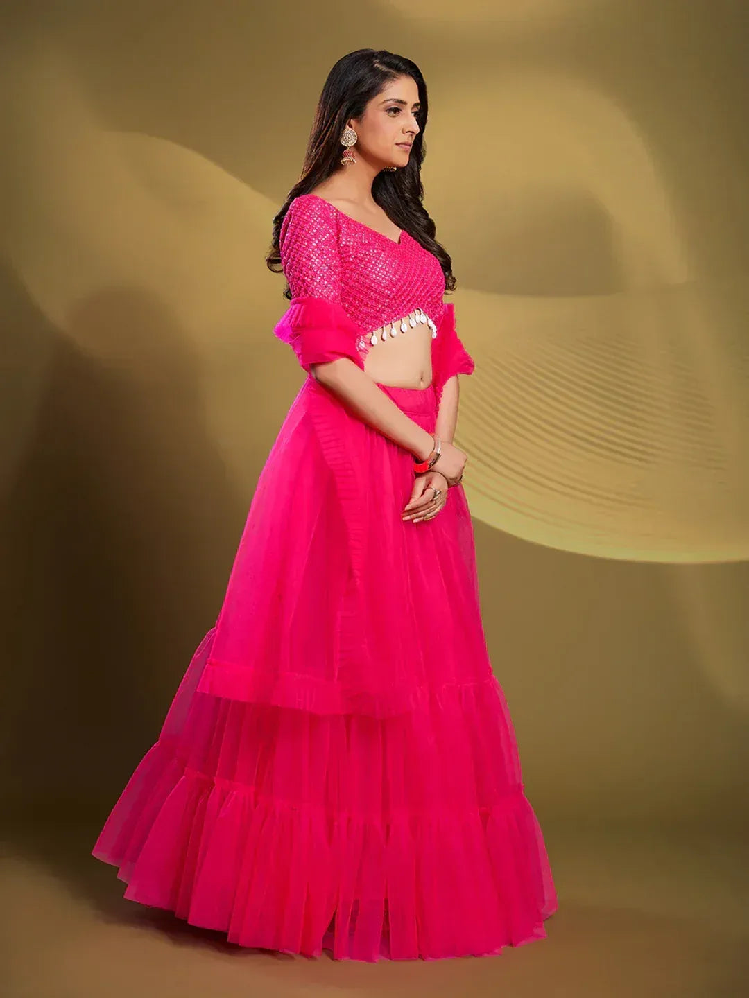 Vibrant pink lehenga choli with ruffled skirt and embellished blouse, perfect for Indian ethnic occasions.
