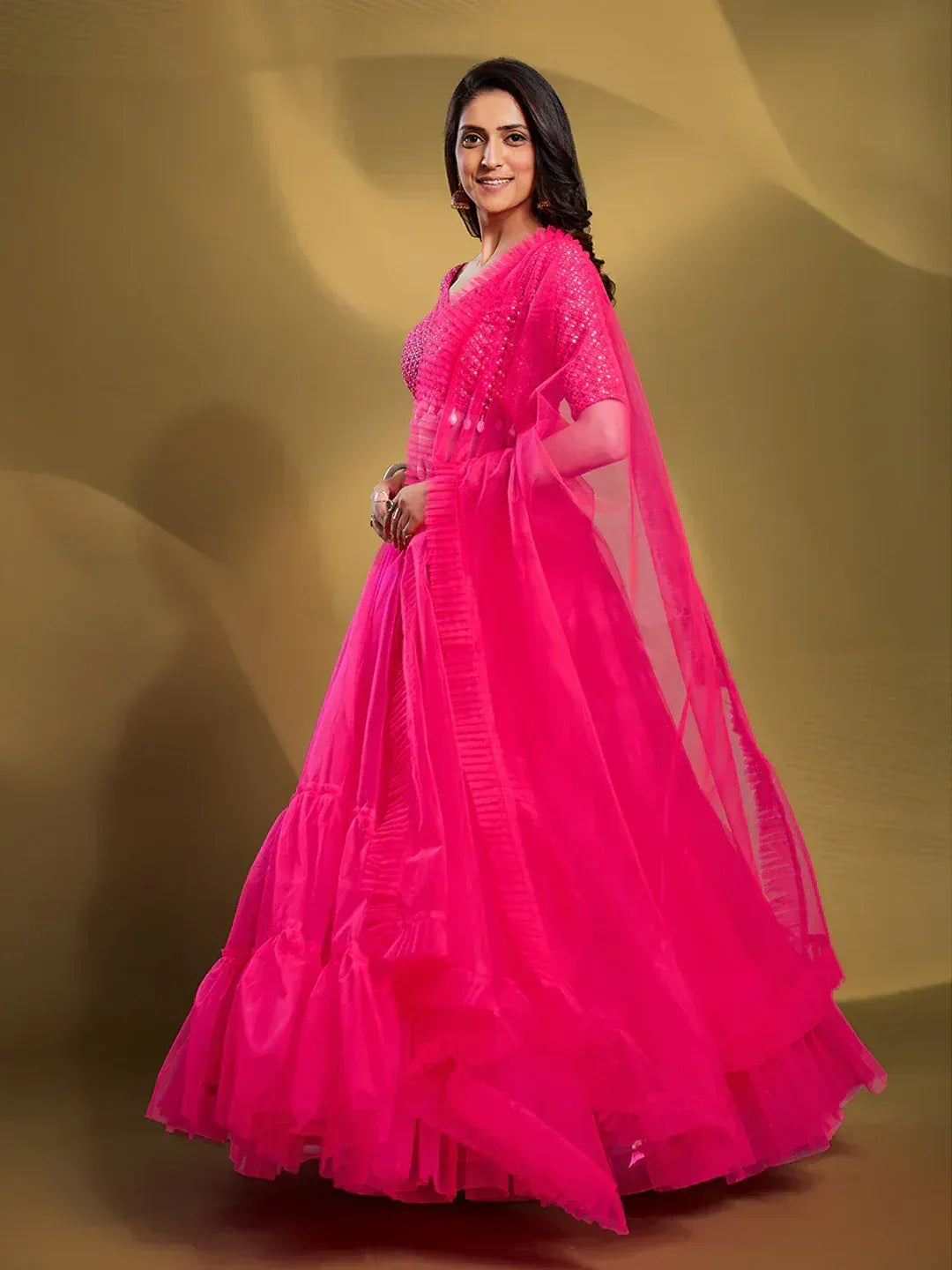 Vibrant pink designer lehenga choli with ruffled layers and sheer dupatta for ethnic wear