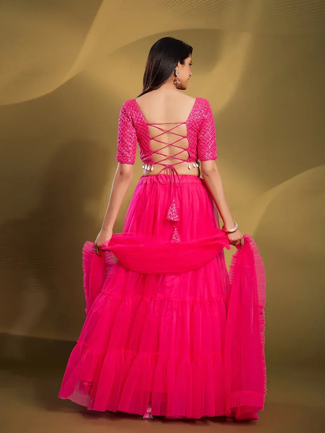 Vibrant pink lehenga choli with lace-up back and layered skirt, perfect for Indian ethnic wear.