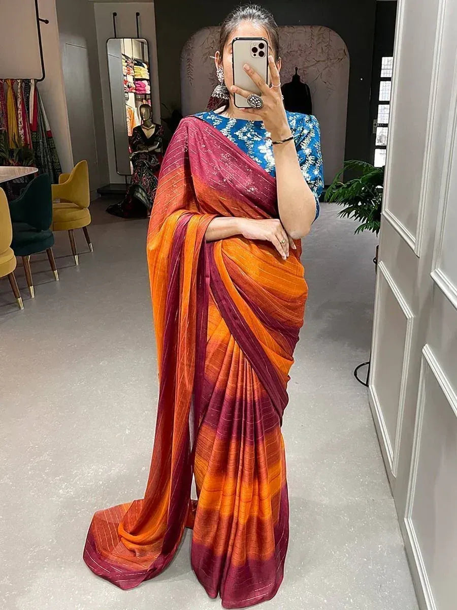 Woman in vibrant orange and maroon ombre saree with blue printed blouse, perfect for Indian ethnic occasions.