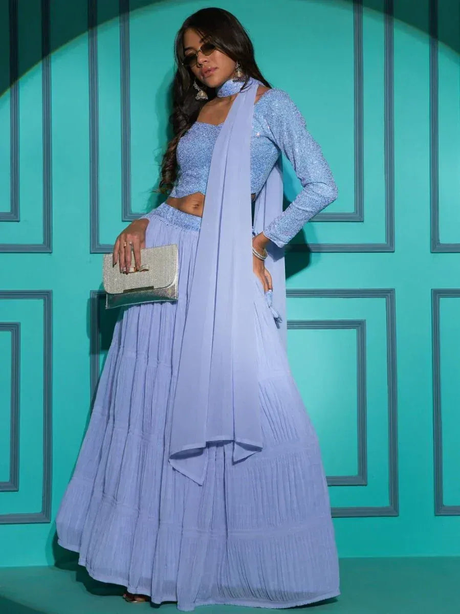 Light blue pleated lehenga choli with sequin top and matching dupatta, styled with clutch and sunglasses