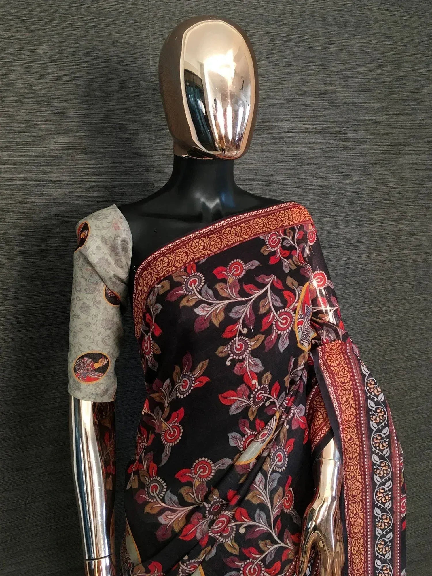 Black floral printed saree with red border and matching blouse, displayed on mannequin