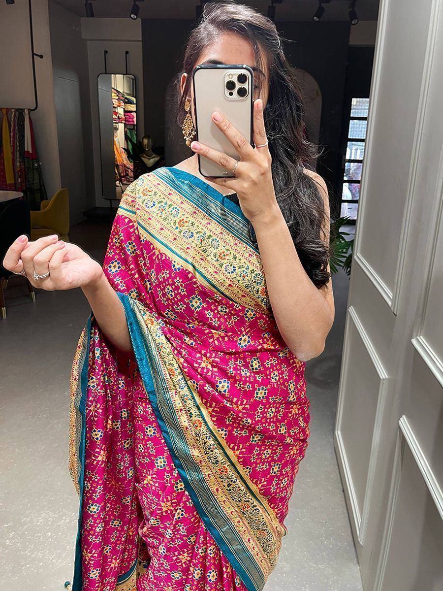 Vibrant pink saree with intricate floral patterns and blue-gold border, styled elegantly for ethnic wear.