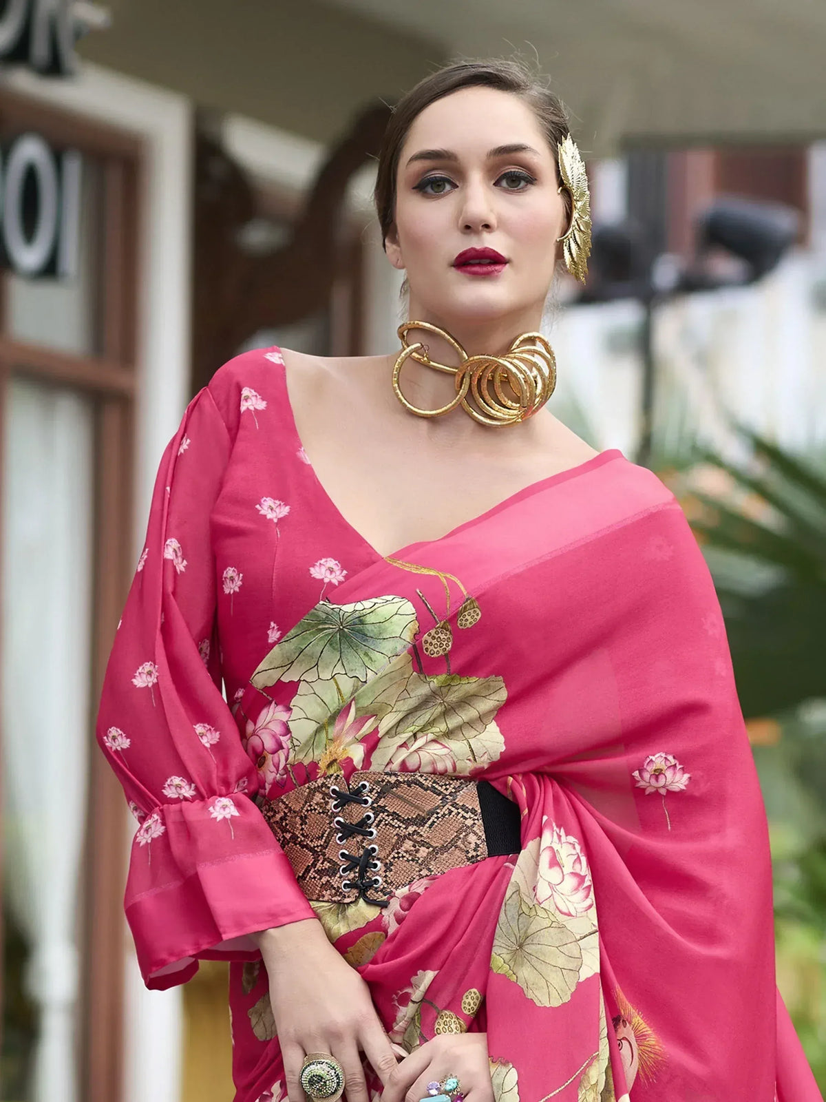 Pink floral saree with lotus print, gold jewelry, and snake print belt for ethnic wear