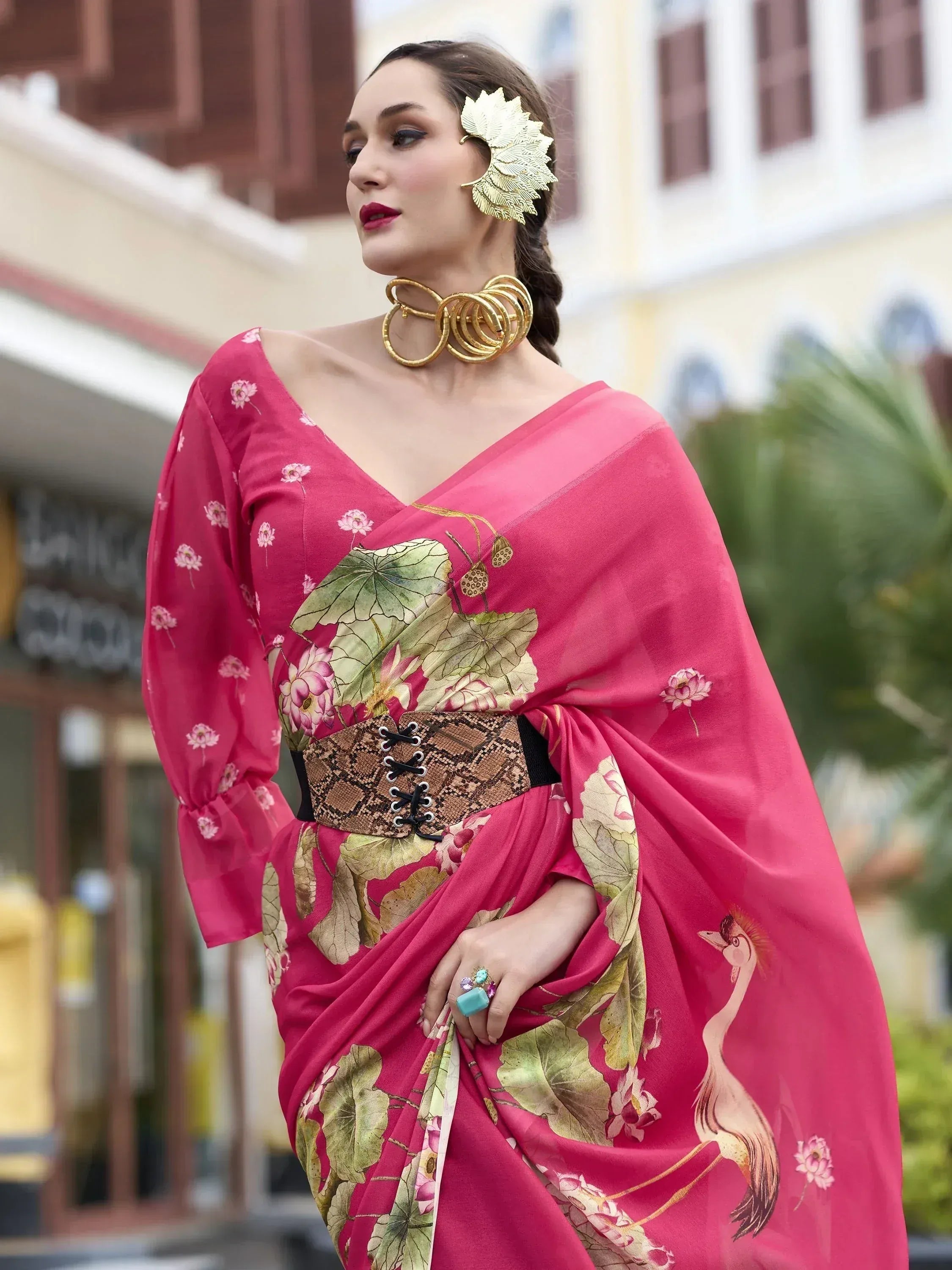 Pink floral saree with lotus print, gold accessories, and snake belt for ethnic wear