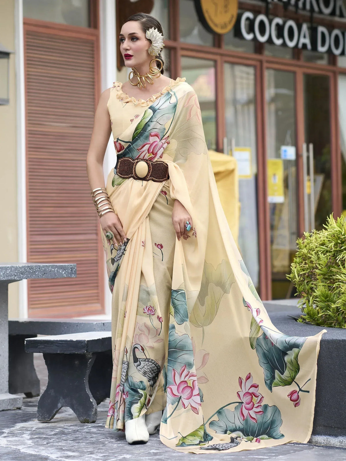 Elegant beige saree with floral and bird print, styled with gold jewelry and belt for ethnic wear