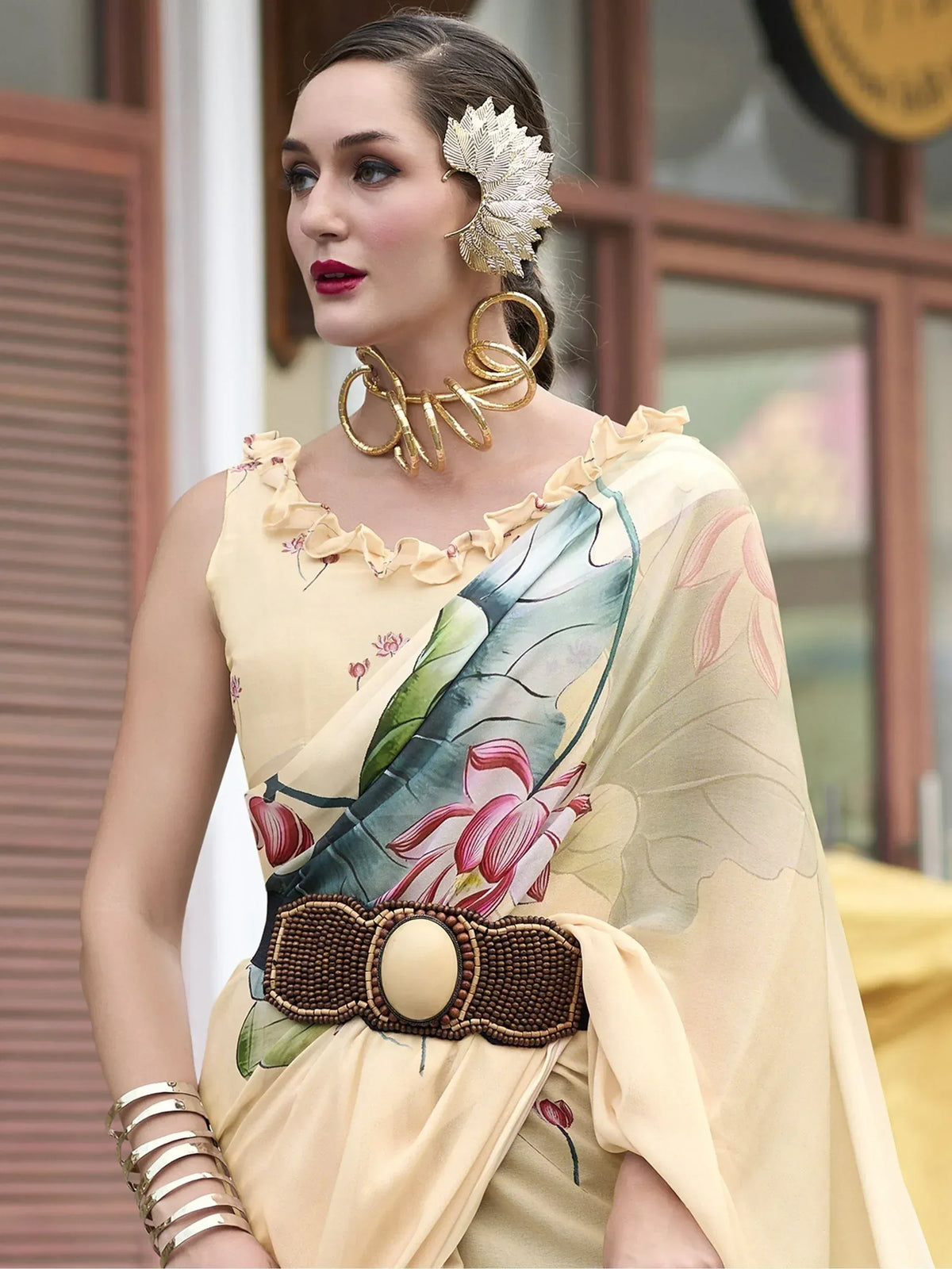 Elegant woman in floral print saree with ruffled neckline, gold jewelry, and beaded belt, showcasing Indian ethnic wear.