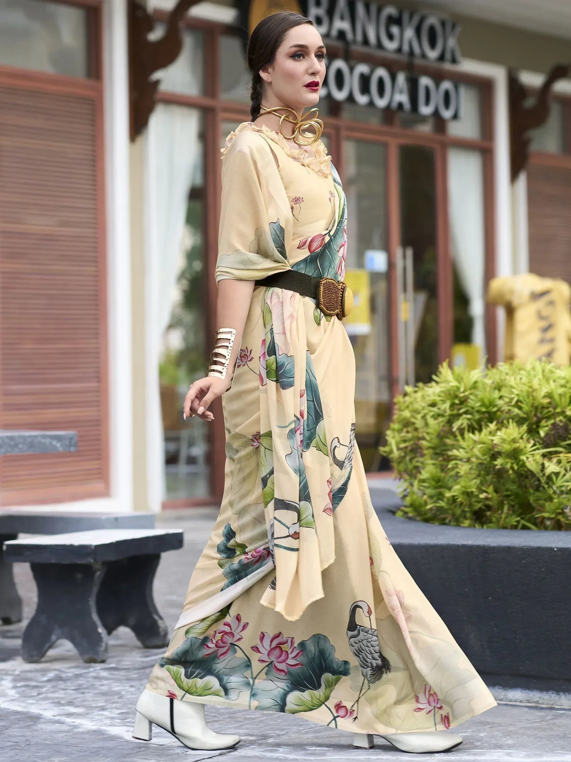 Woman in floral print ethnic gown with lotus design, styled with belt and gold jewelry for modern Indian wear