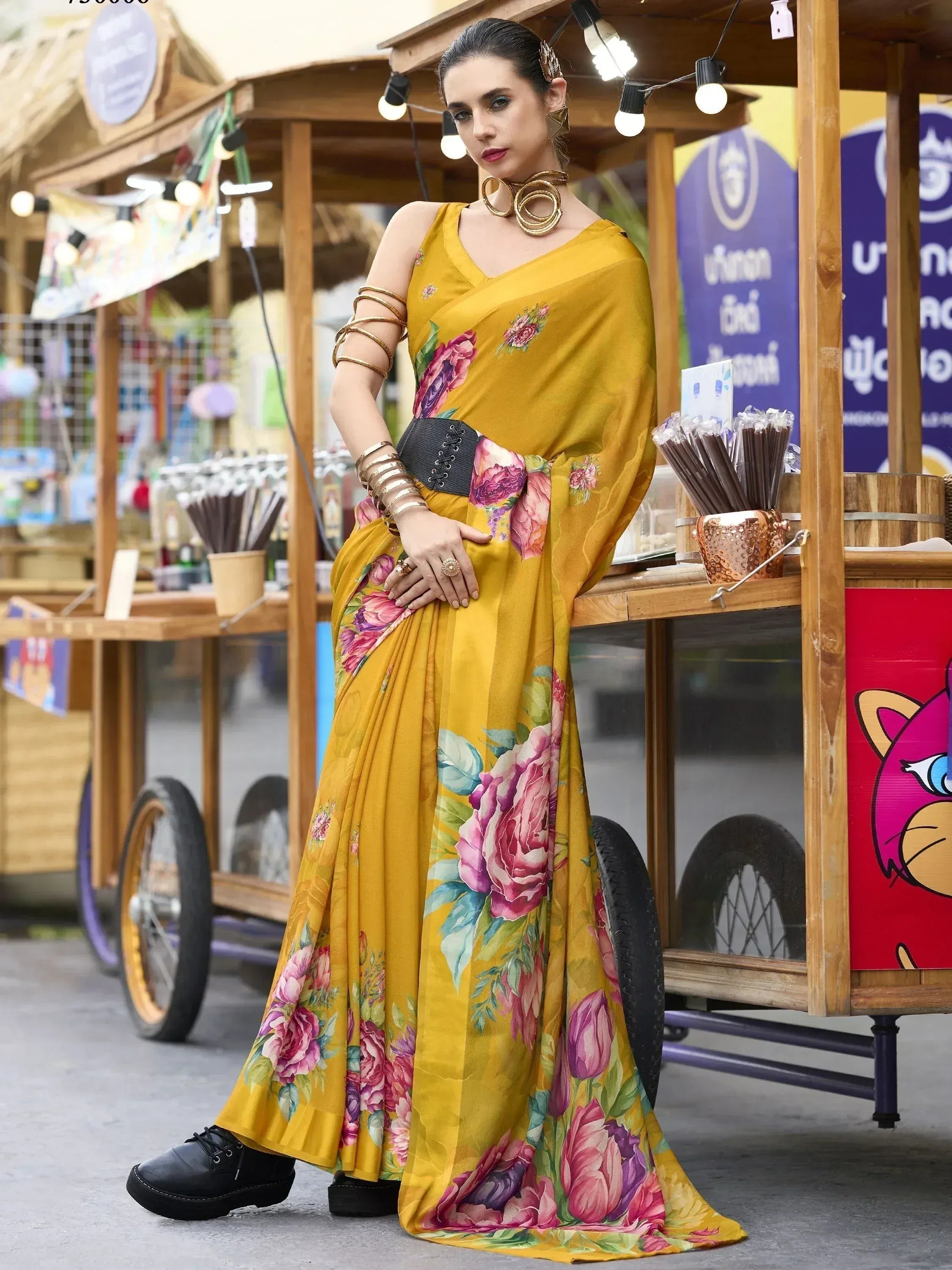 Mustard floral saree with bold print, styled with black corset belt and gold jewelry for ethnic fashion