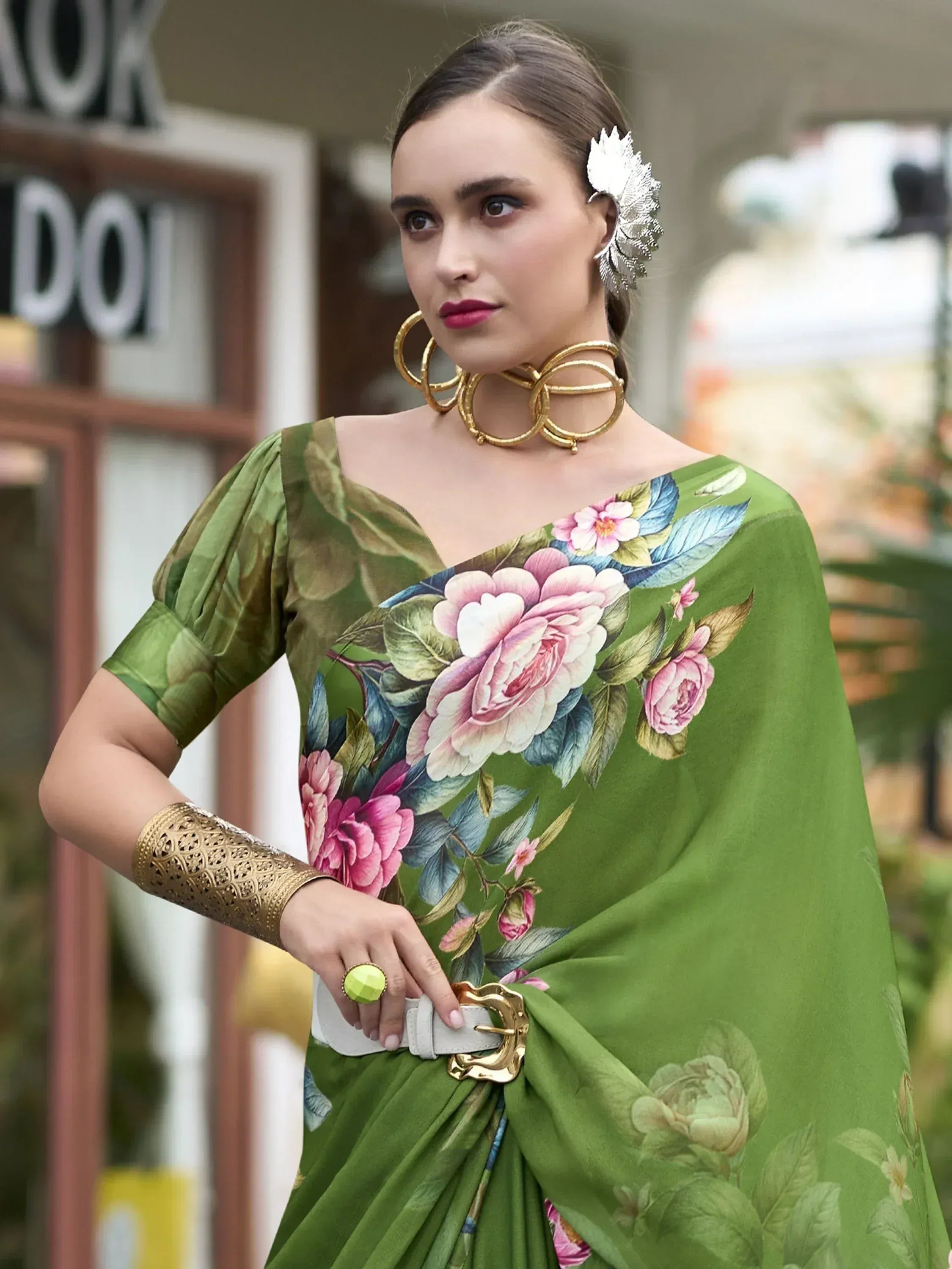 Green floral saree with pink roses, gold jewelry, and white belt for ethnic wear
