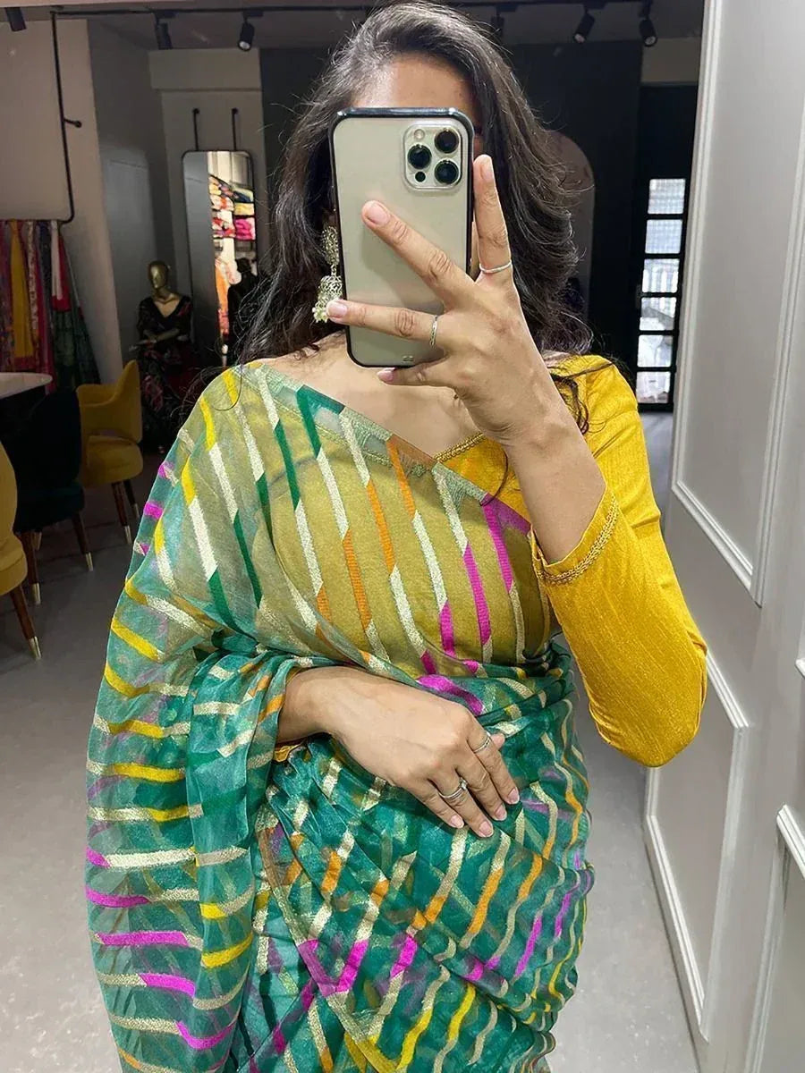Woman in colorful striped saree with yellow blouse, taking mirror selfie in boutique