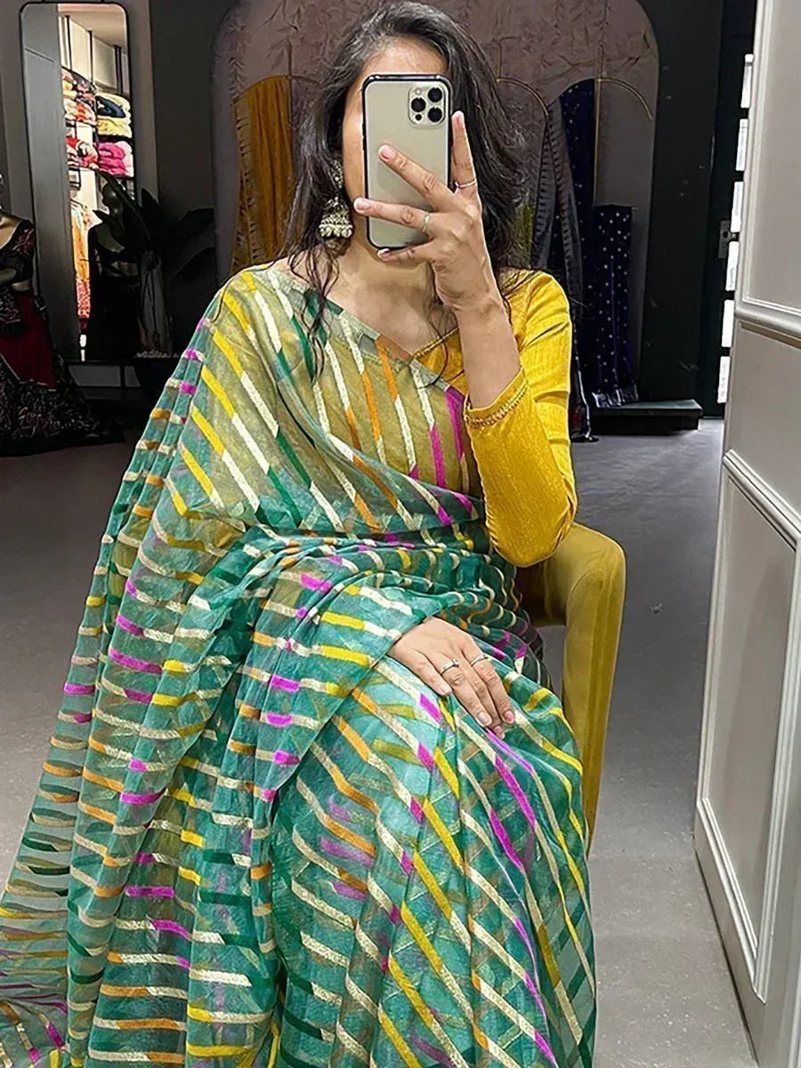 Woman in vibrant green and yellow striped saree with pink accents, paired with yellow blouse, taking mirror selfie.