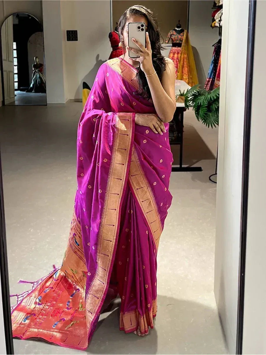 Woman wearing vibrant pink ethnic saree with gold border, taking mirror selfie in boutique