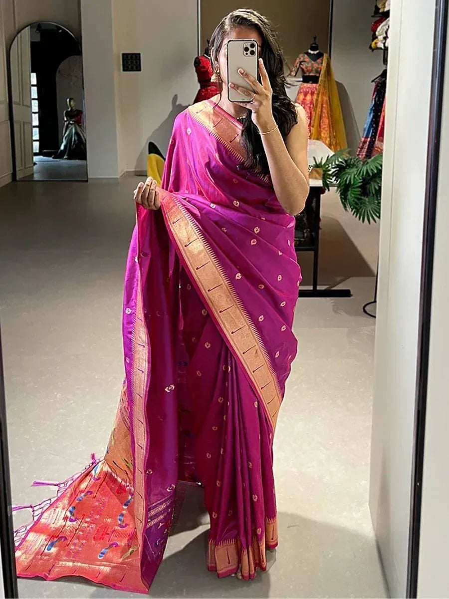 Woman wearing vibrant pink Indian saree with gold border, taking mirror selfie in boutique