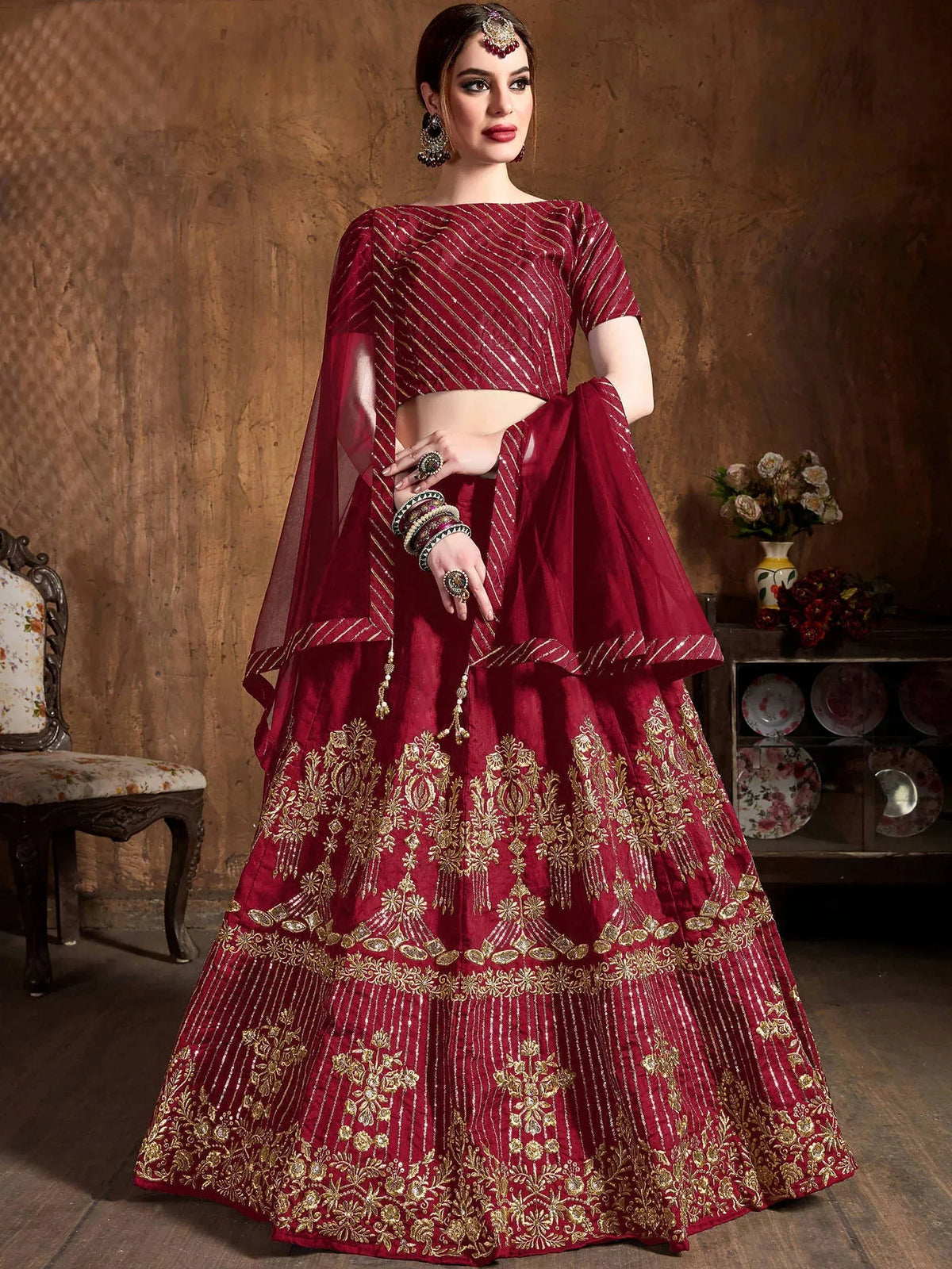 Woman wearing a maroon designer lehenga choli with gold embroidery and sequins