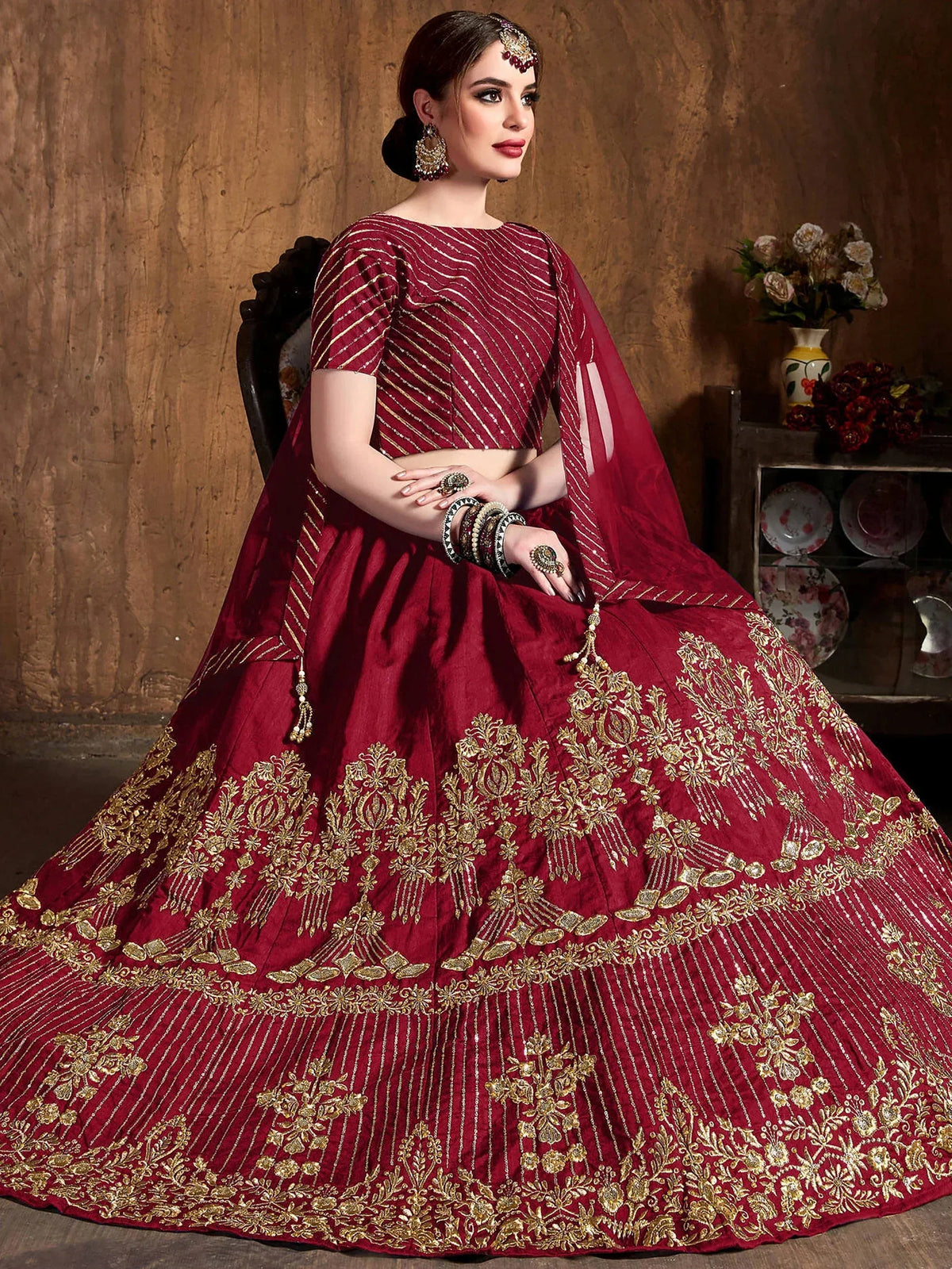 Woman wearing a maroon designer lehenga choli with intricate gold embroidery
