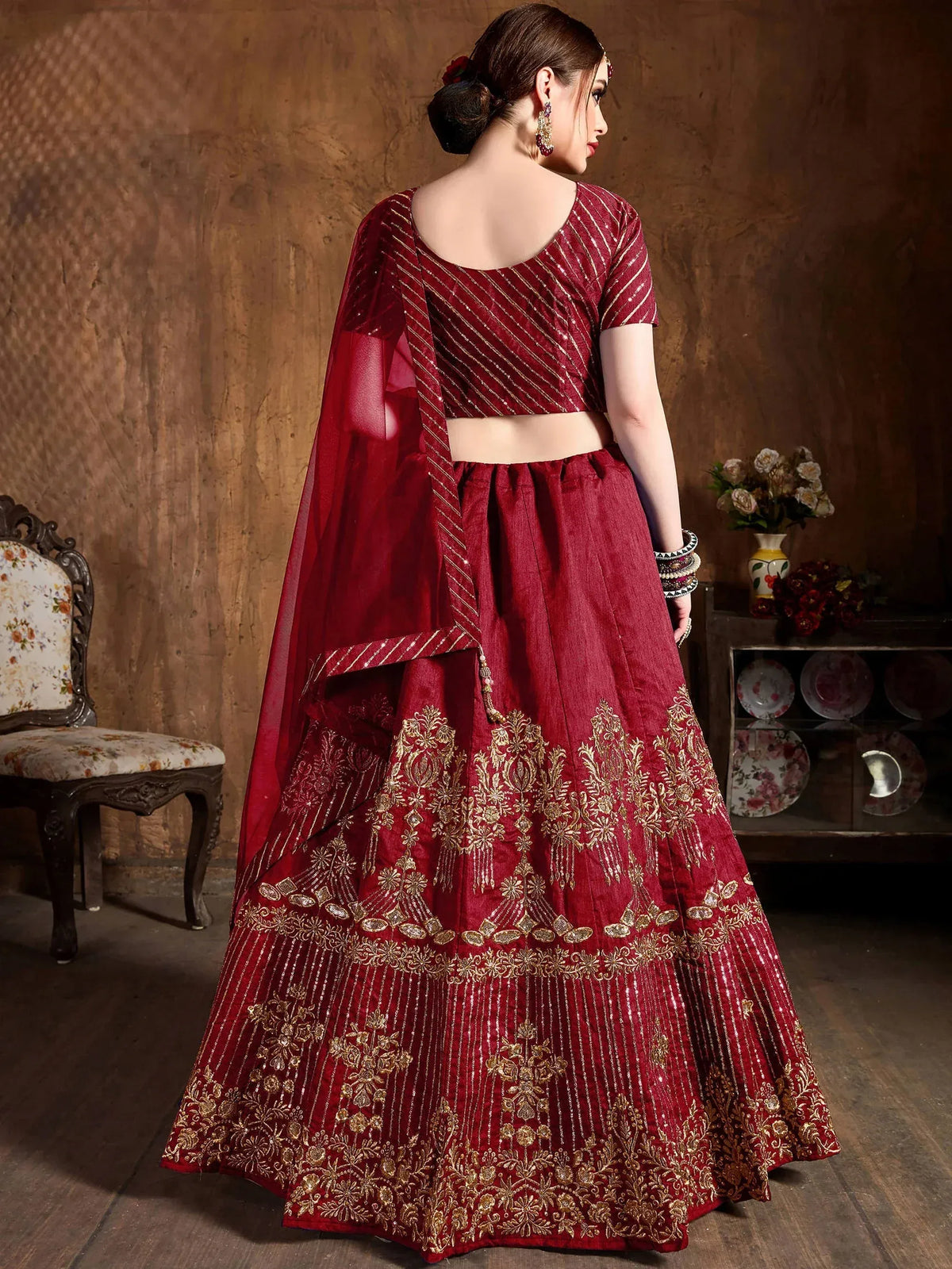 Back view of a woman wearing a maroon embroidered designer lehenga choli with a dupatta