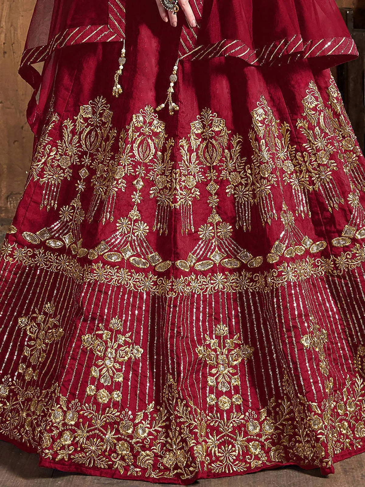 Detailed view of a maroon lehenga with intricate gold embroidery and sequin work