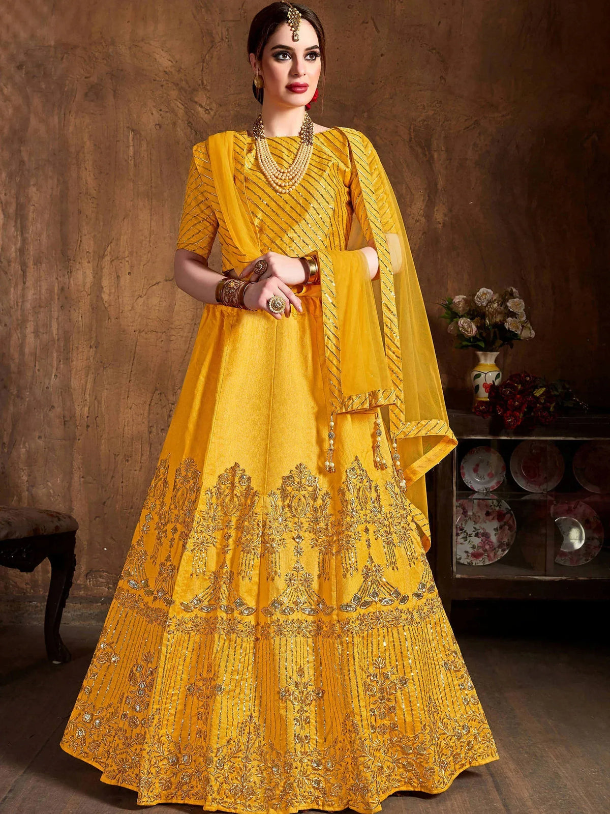 Woman wearing a yellow embroidered designer ethnic gown with a matching dupatta