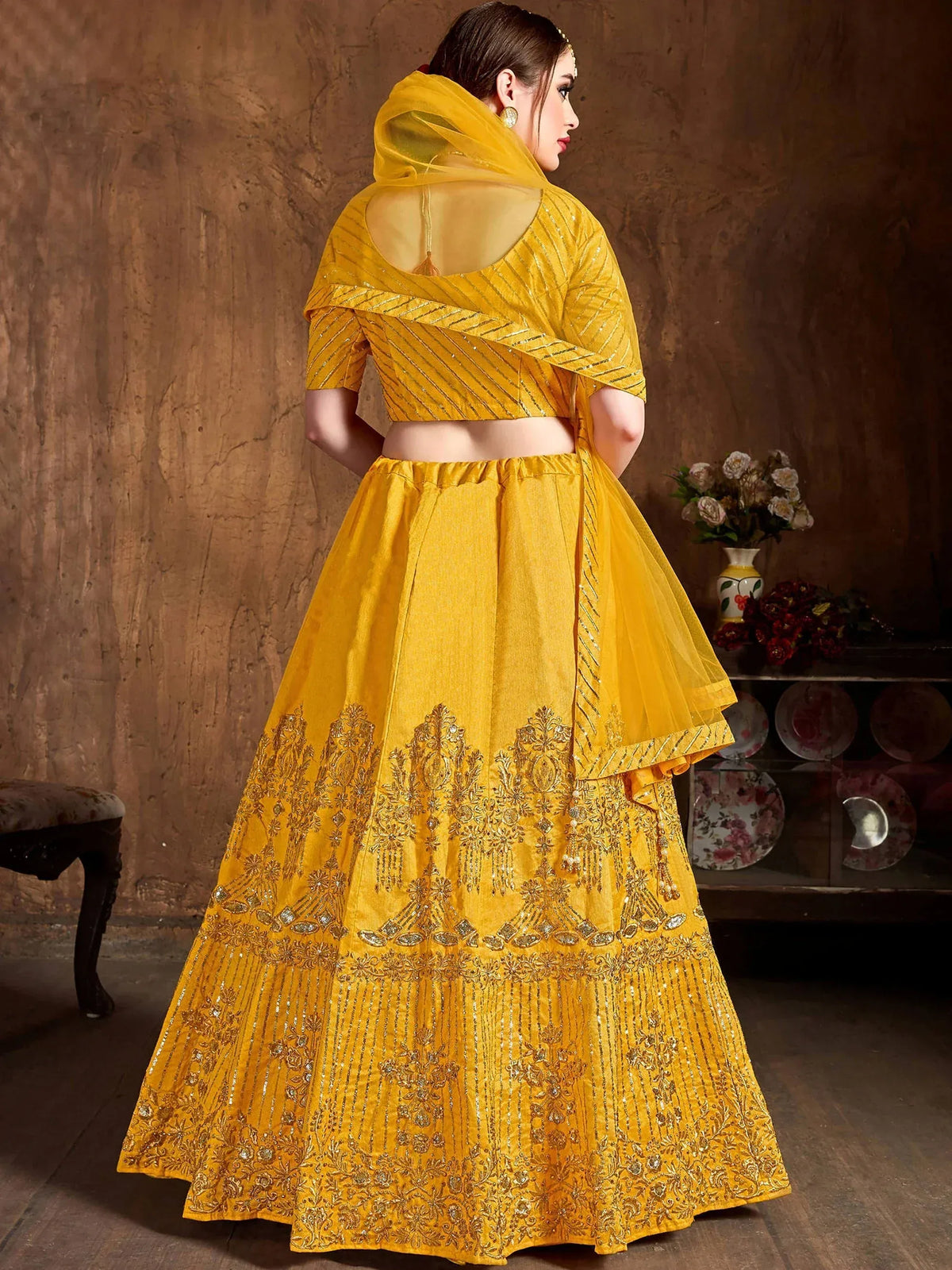 Woman wearing a yellow designer lehenga choli with intricate embroidery