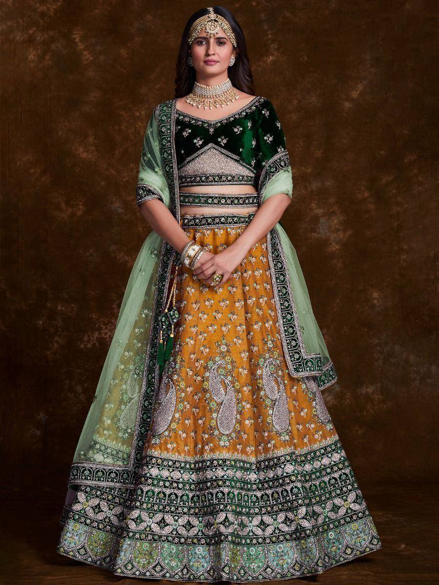 Emerald green velvet blouse with mustard yellow floral lehenga, paired with sheer dupatta and traditional jewelry
