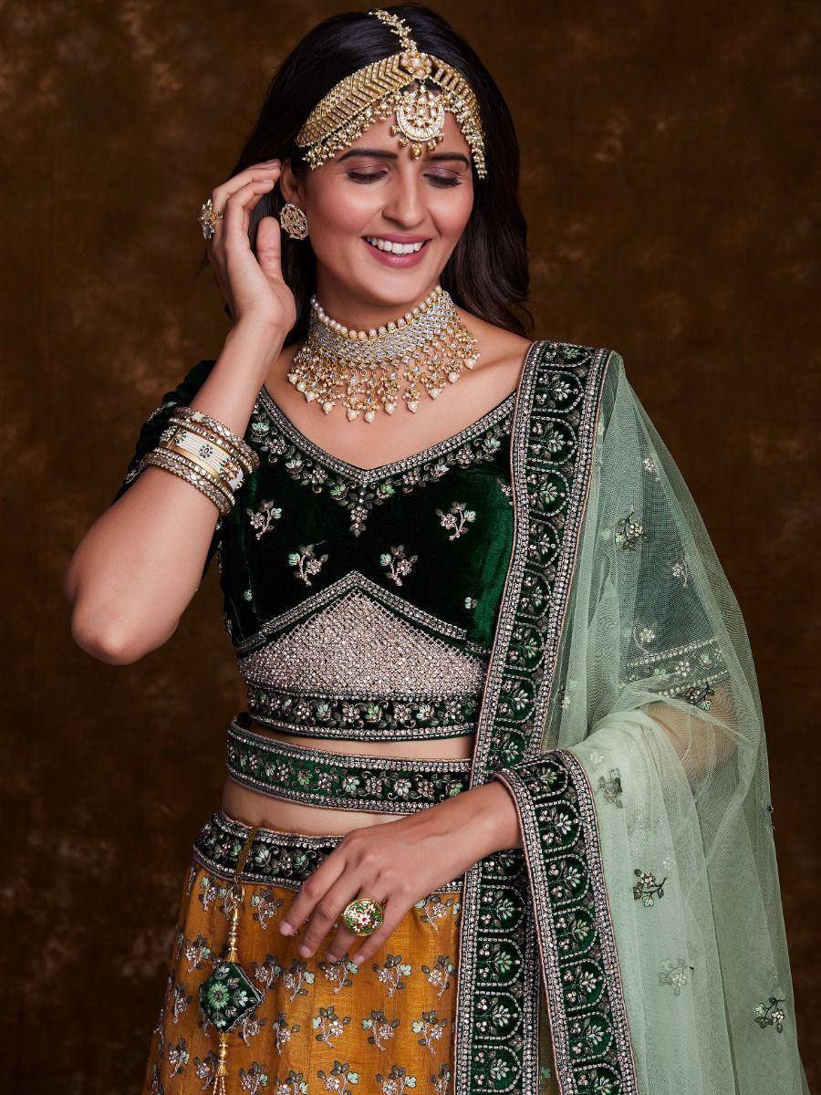Green velvet lehenga choli with gold embroidery, matching dupatta, and traditional Indian bridal jewelry