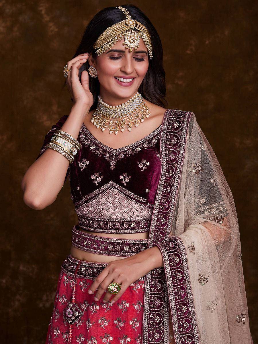 Elegant maroon velvet lehenga choli with gold embroidery, paired with traditional Indian jewelry and dupatta