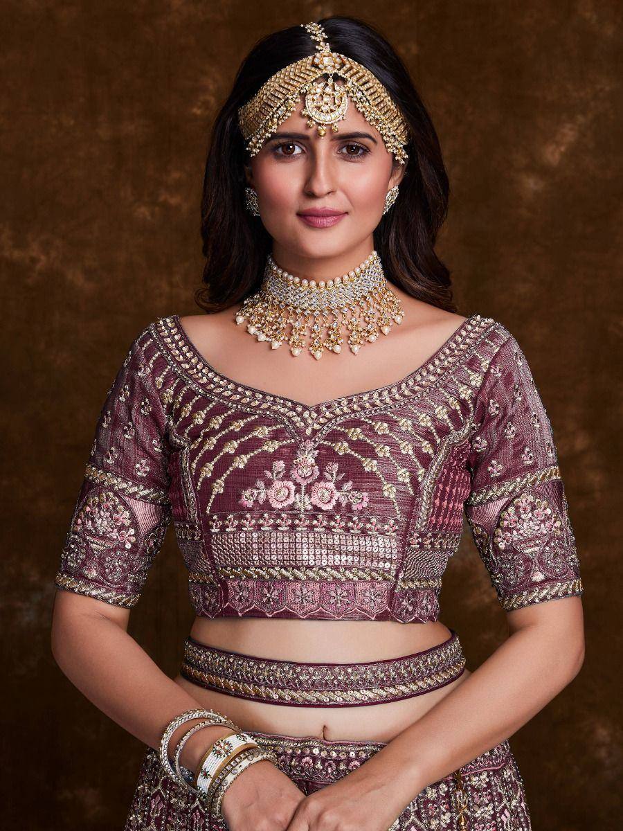 Maroon embroidered lehenga choli with gold jewelry, perfect for Indian weddings and festive occasions.