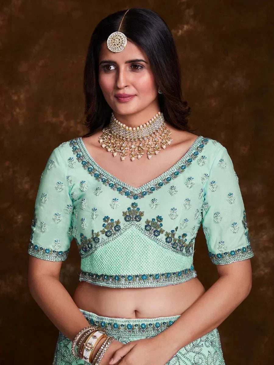 Mint green embroidered lehenga choli with floral motifs and matching jewelry for Indian ethnic wear